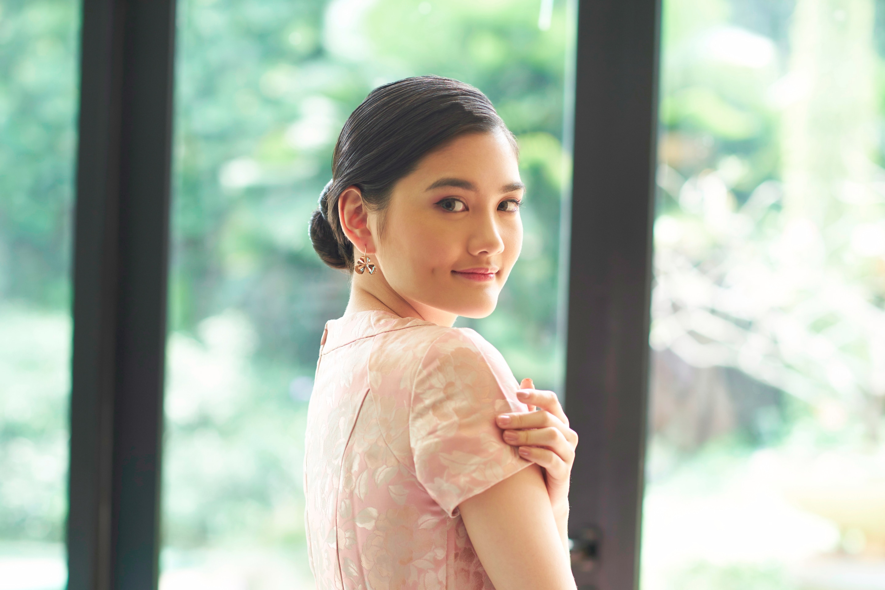 Wanita asia dengan model rambut hitam panjang menunjukkan hasil tatanan rambut side part sleek low bun