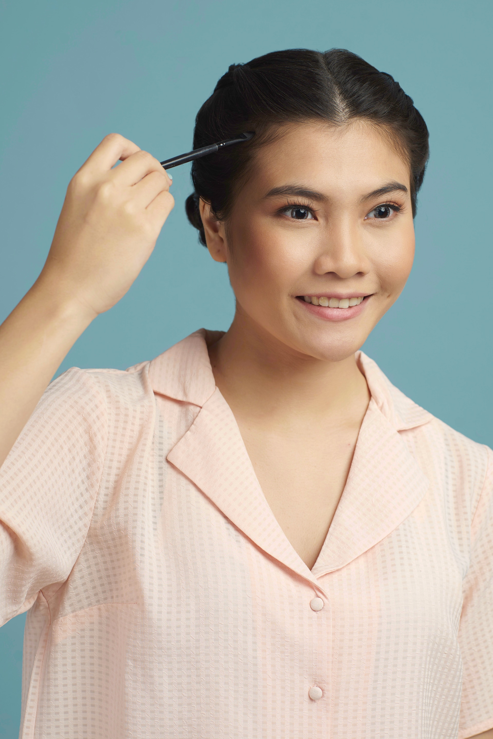 Wanita asia dengan rambut disanggul warna hitam menyapukan kuas ke rambut - double dutch braid bun