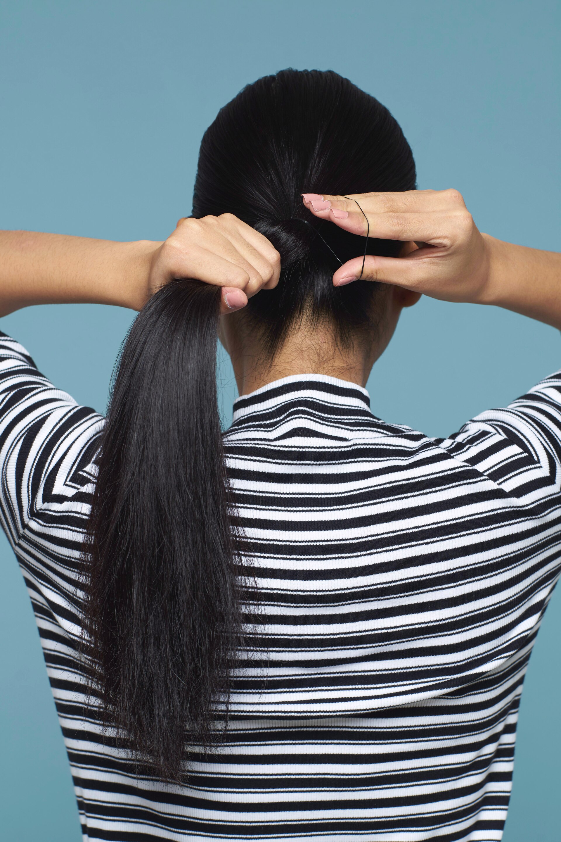 Wanita asia sedang membentuk ponytail pada rambut hitam panjang