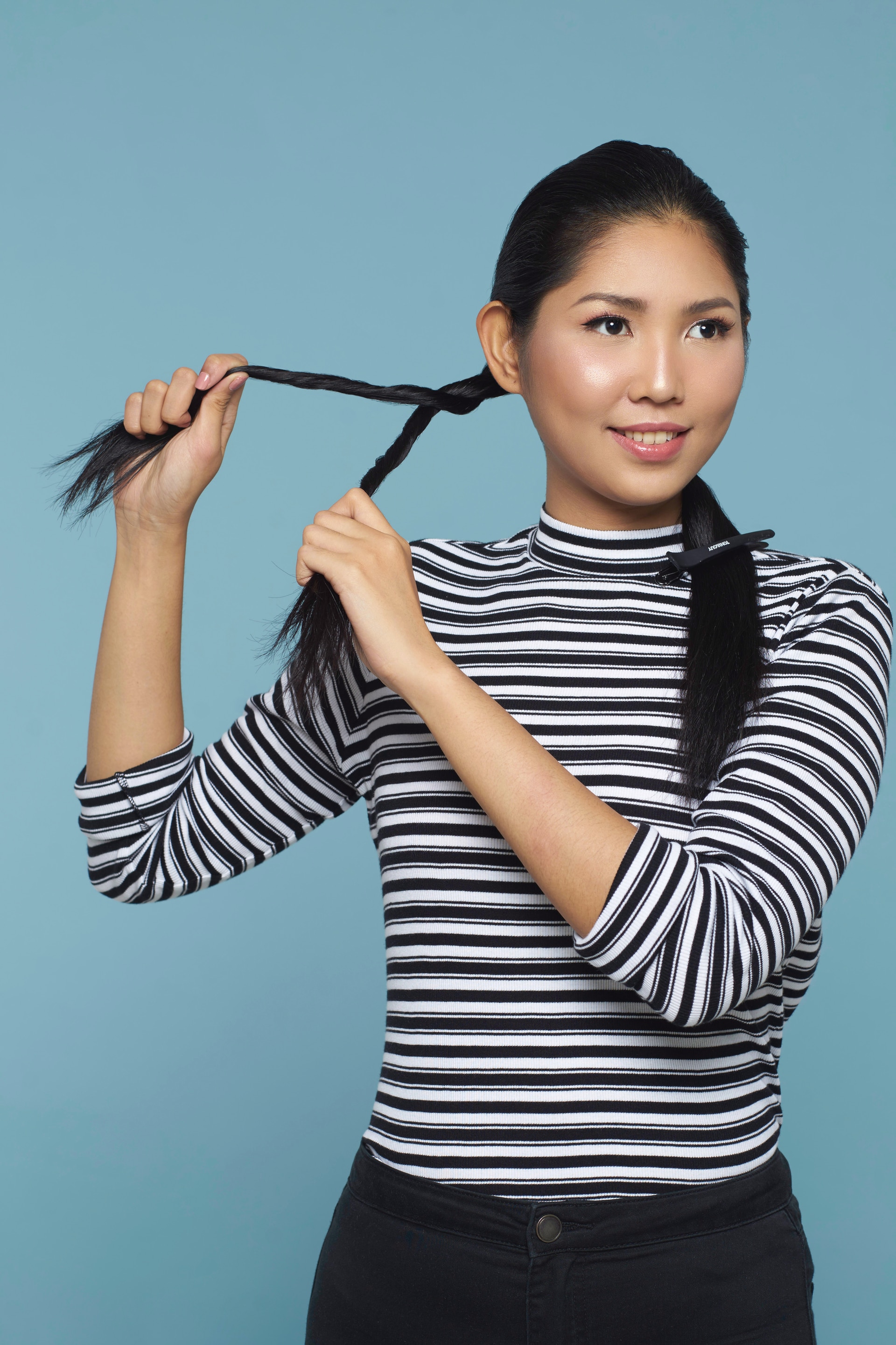 Wanita asia dengan rambut hitam panjang sedang membuat double rope braid ponytail