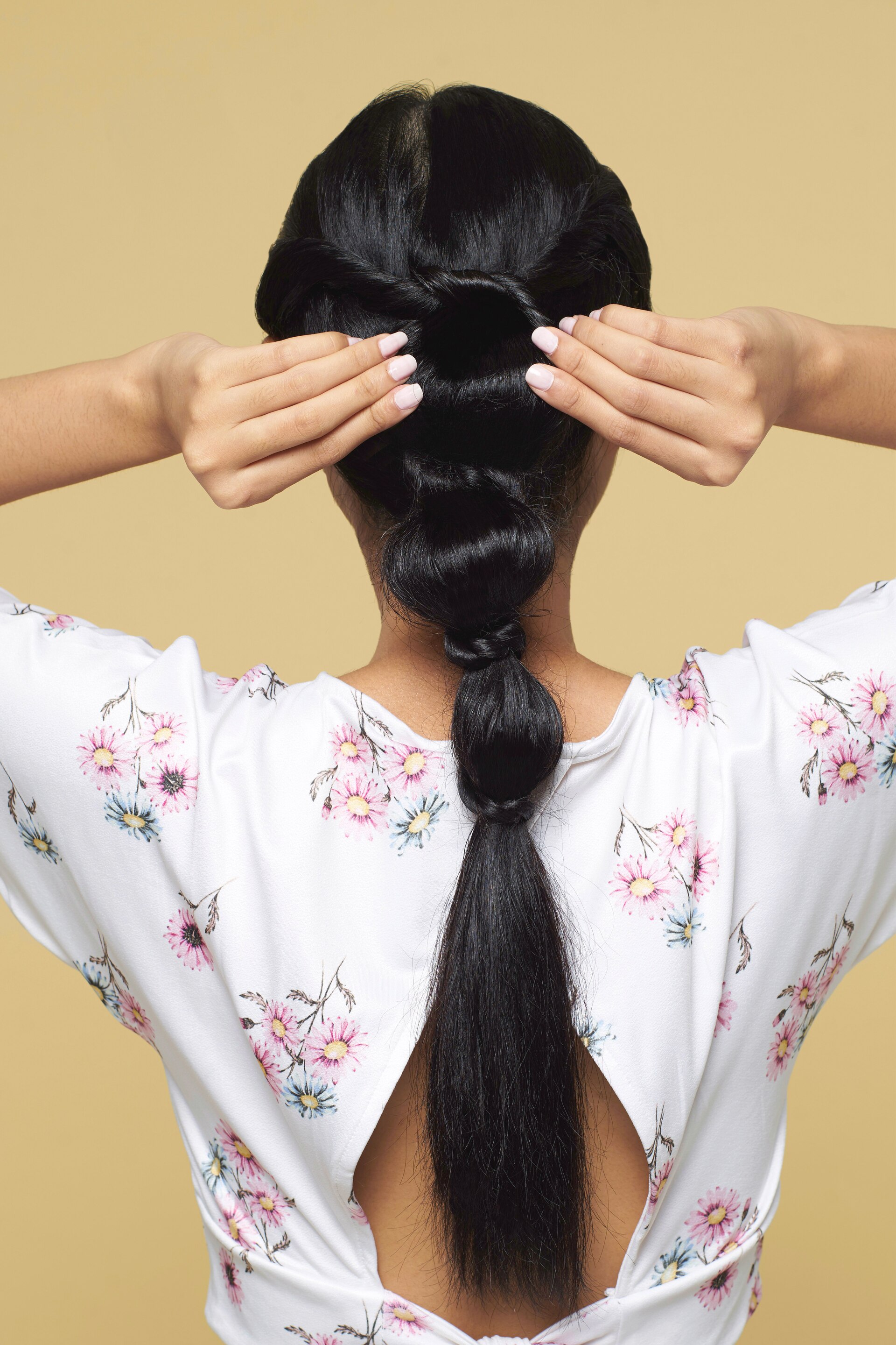 Wanita asia dengan rambut hitam panjang menata rambut dengan gaya knotted bubble ponytail