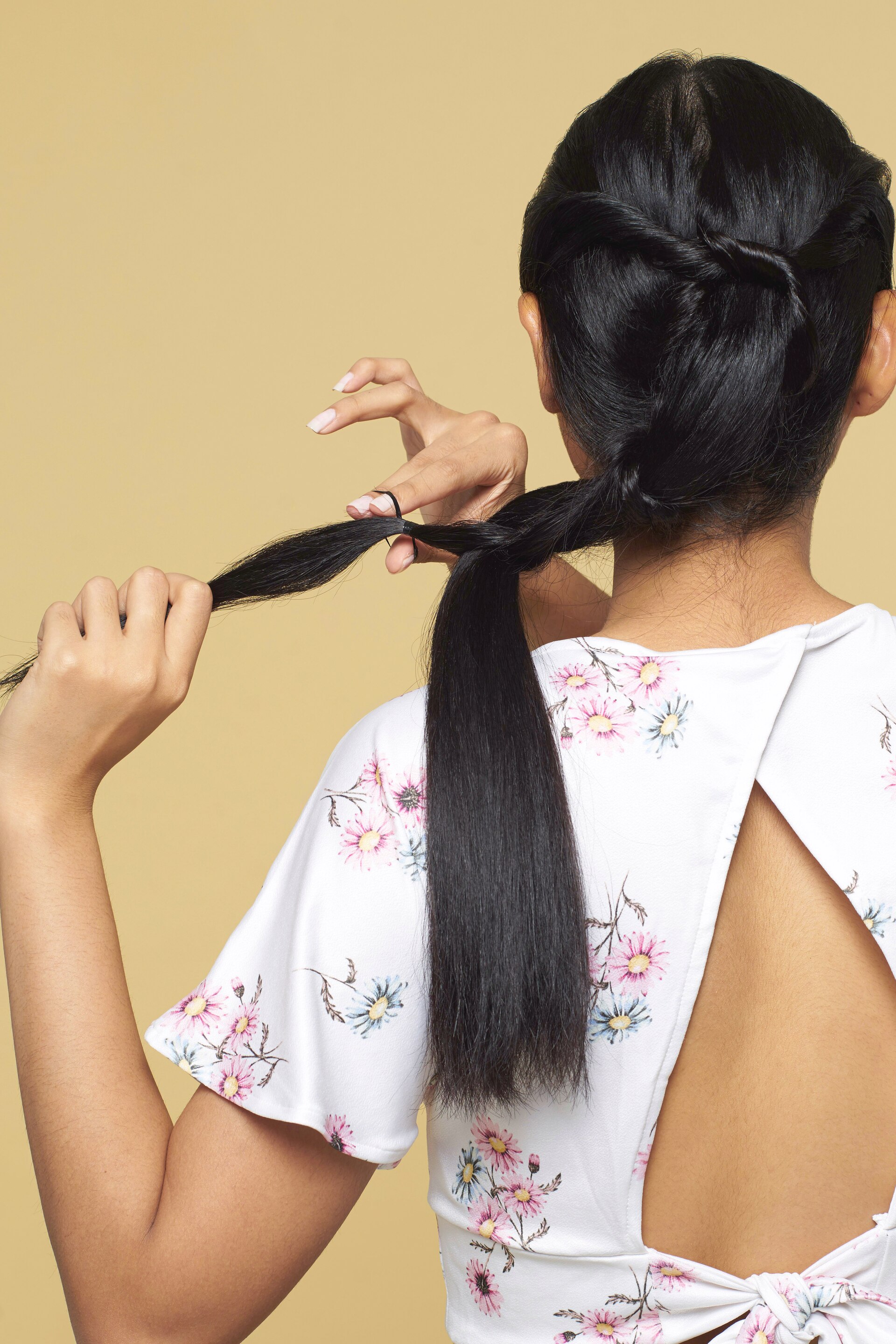 Wanita asia dengan rambut hitam panjang menata rambut dengan gaya knotted bubble ponytail