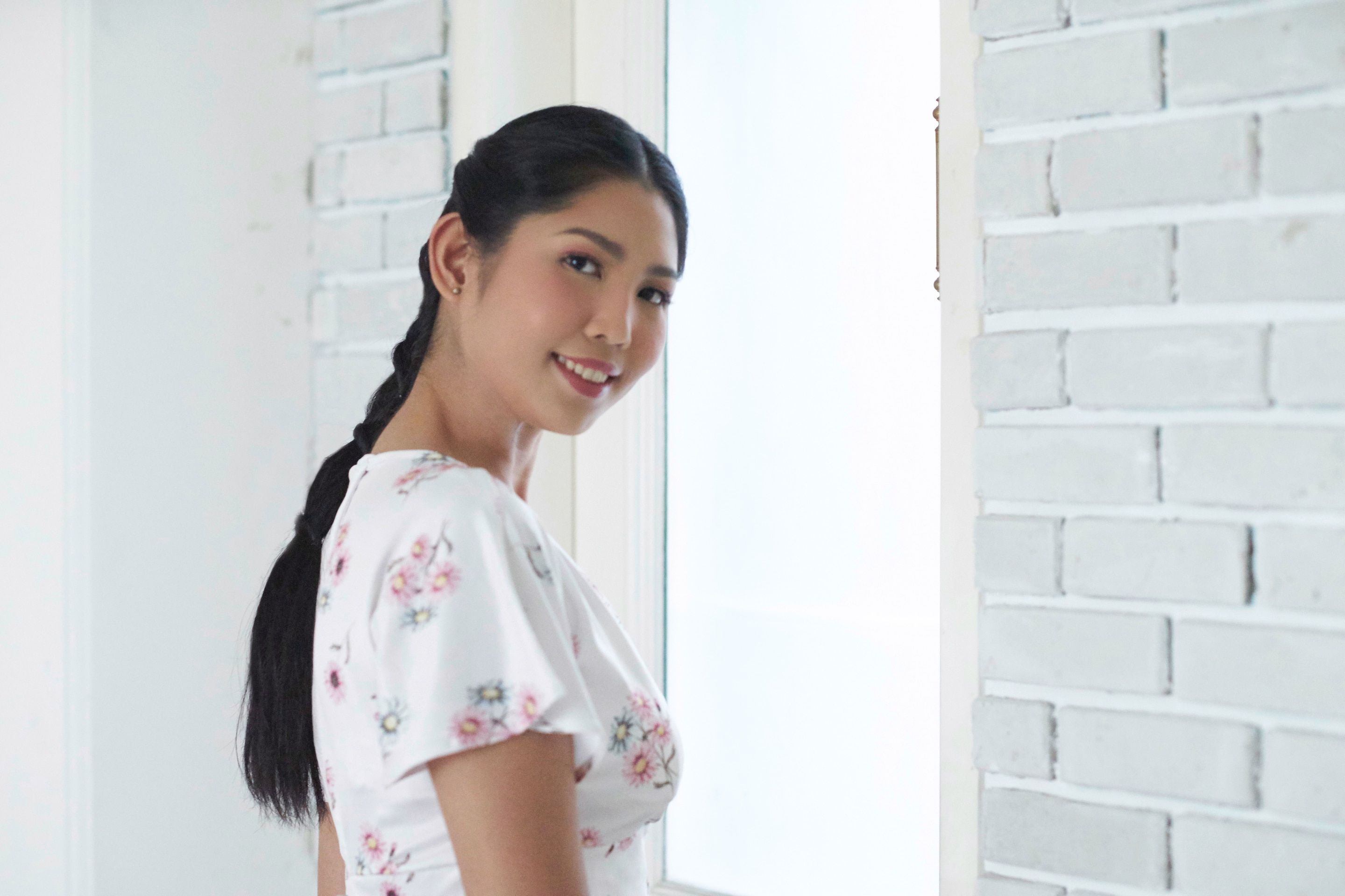 Wanita asia dengan rambut hitam panjang menata rambut dengan gaya knotted bubble ponytail