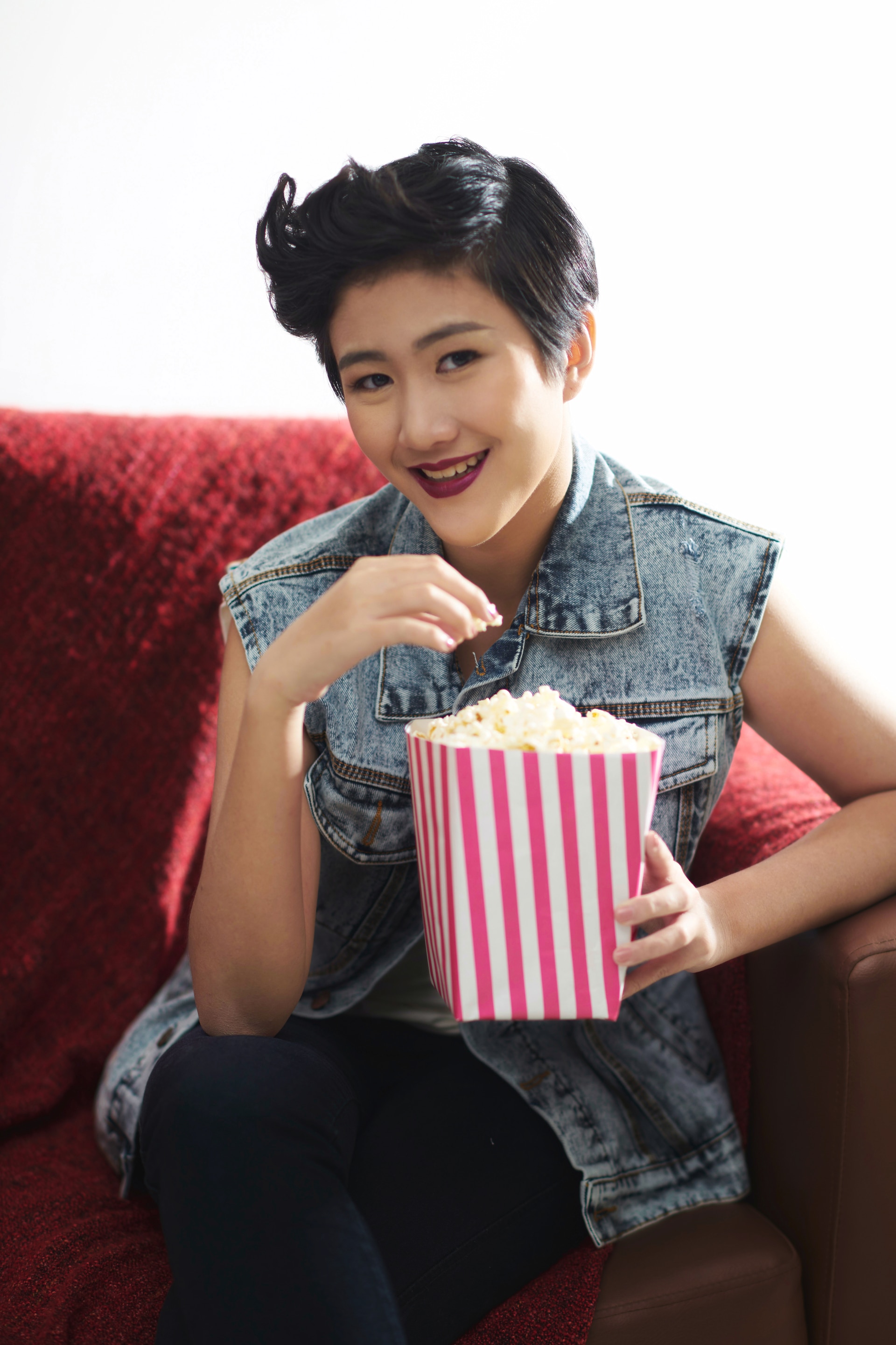 Wanita asia dengan gaya rambut long pixie cuts sedang menyantap popcorn.