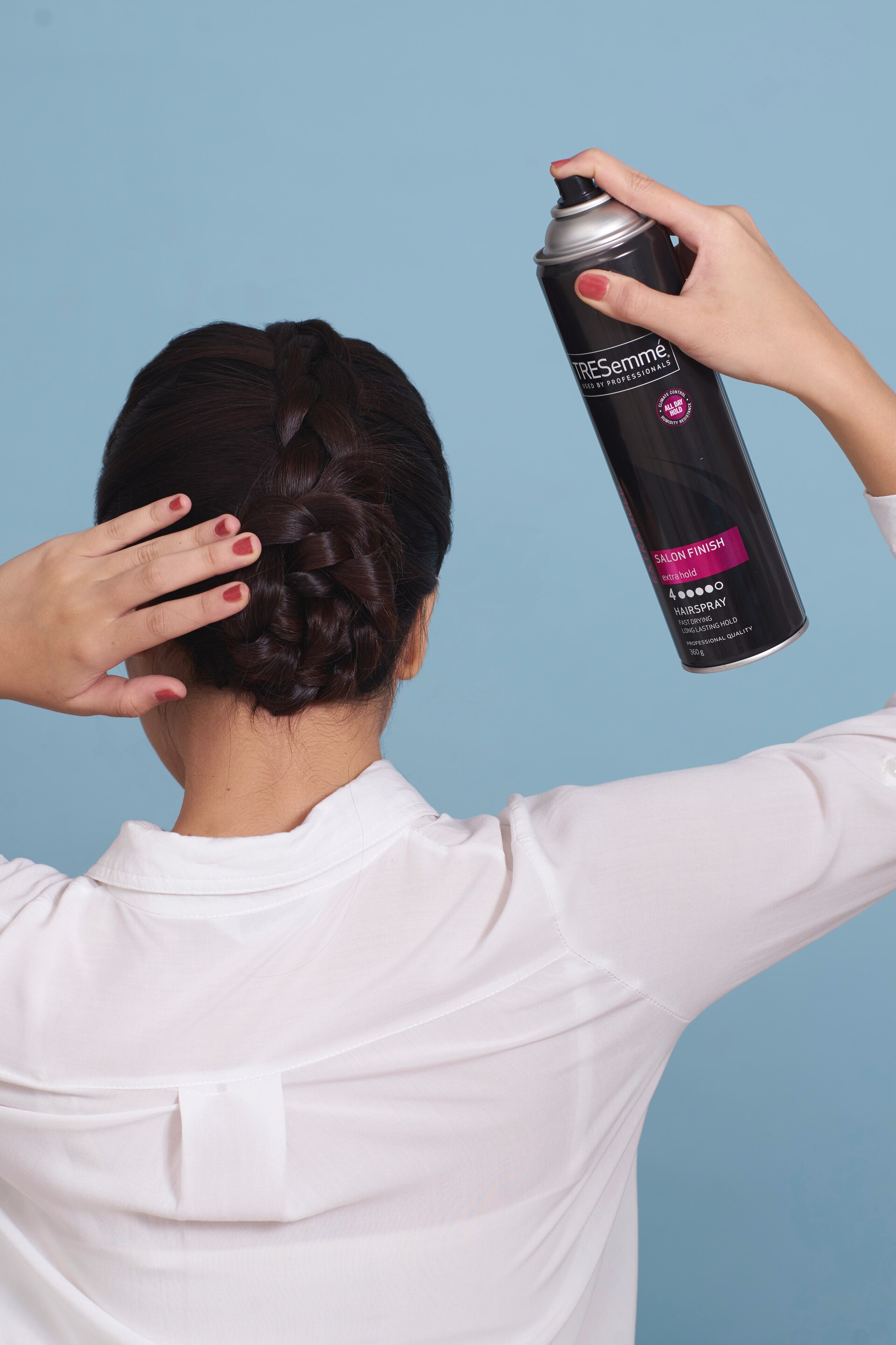wanita asia sedang menyemprot hairspray pada sanggul kepang gaya messy