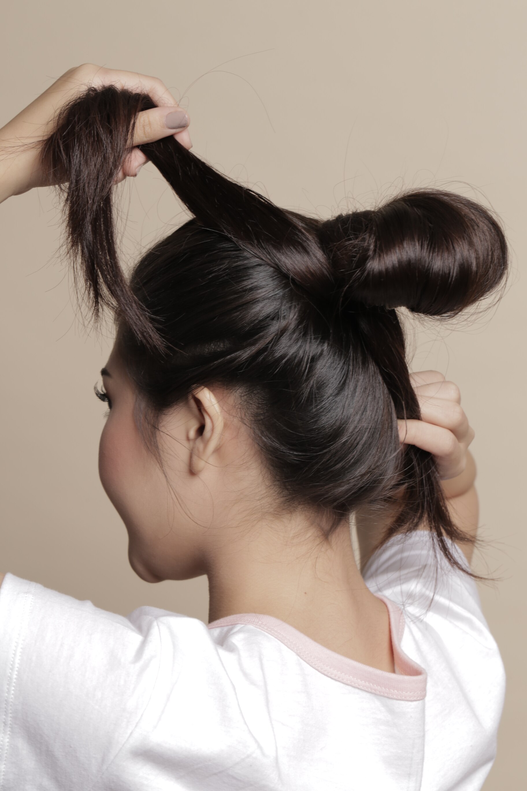 wanita asia berambut hitam sedang mencepiol rambut