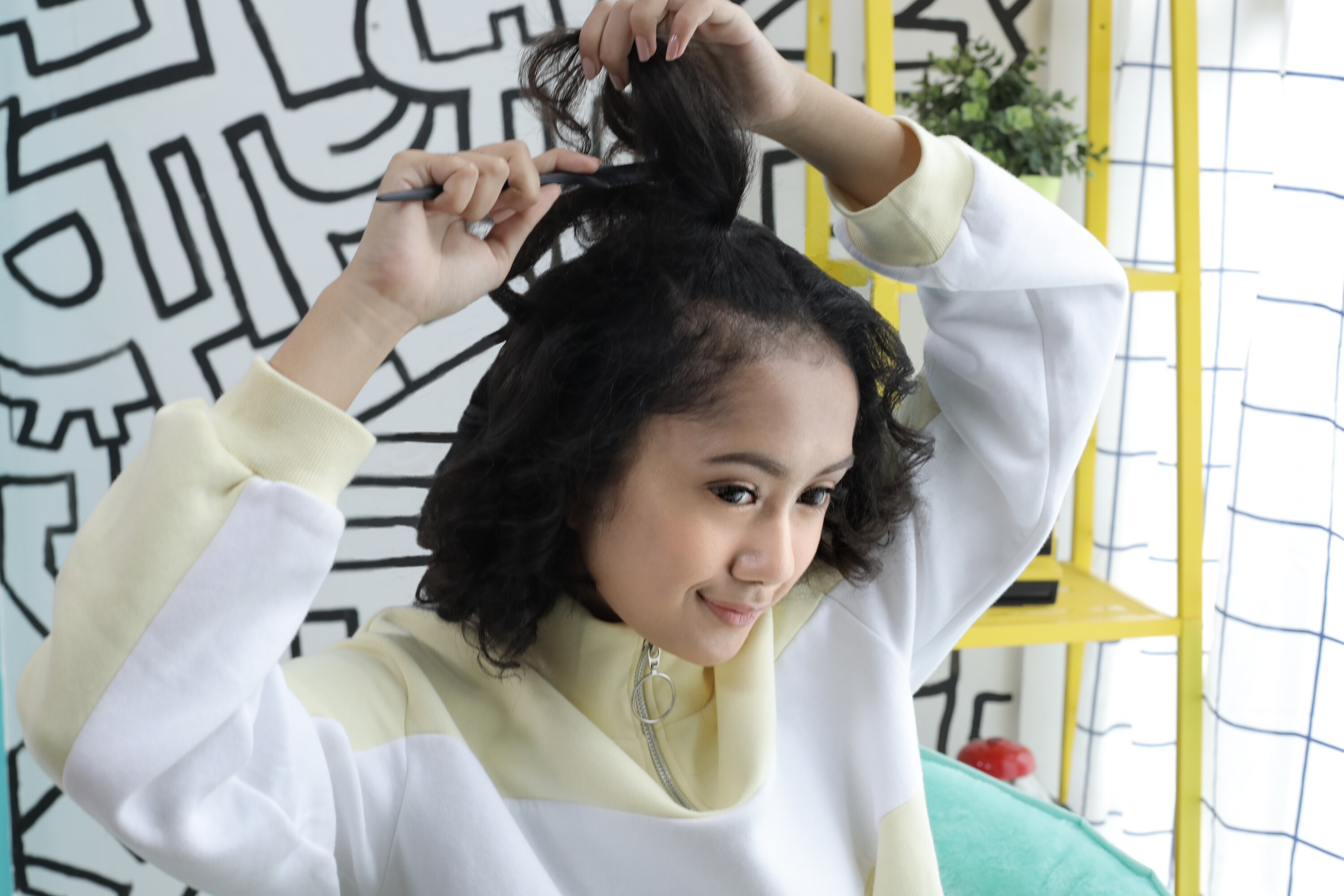 Wanita asia dengan model rambut half space bun untuk rambut keriting