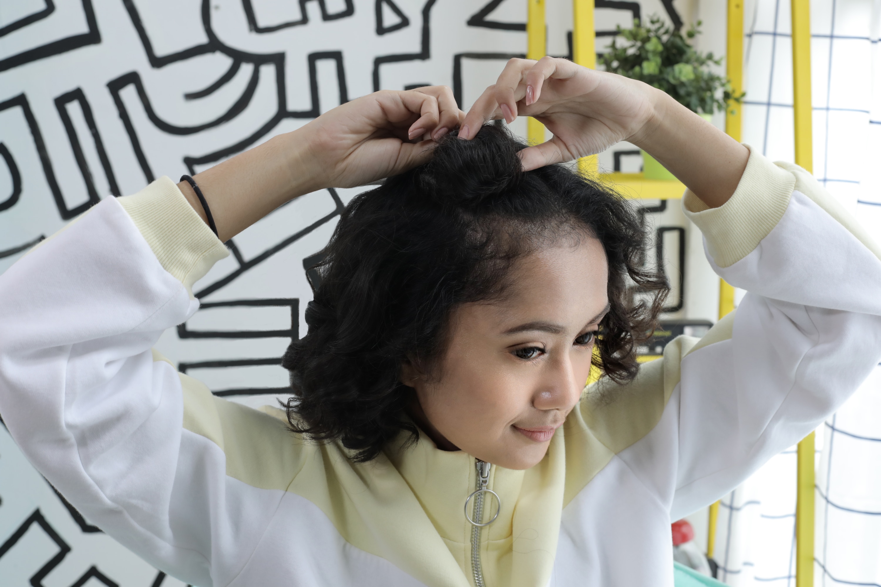 Wanita asia dengan model rambut half space bun untuk rambut keriting