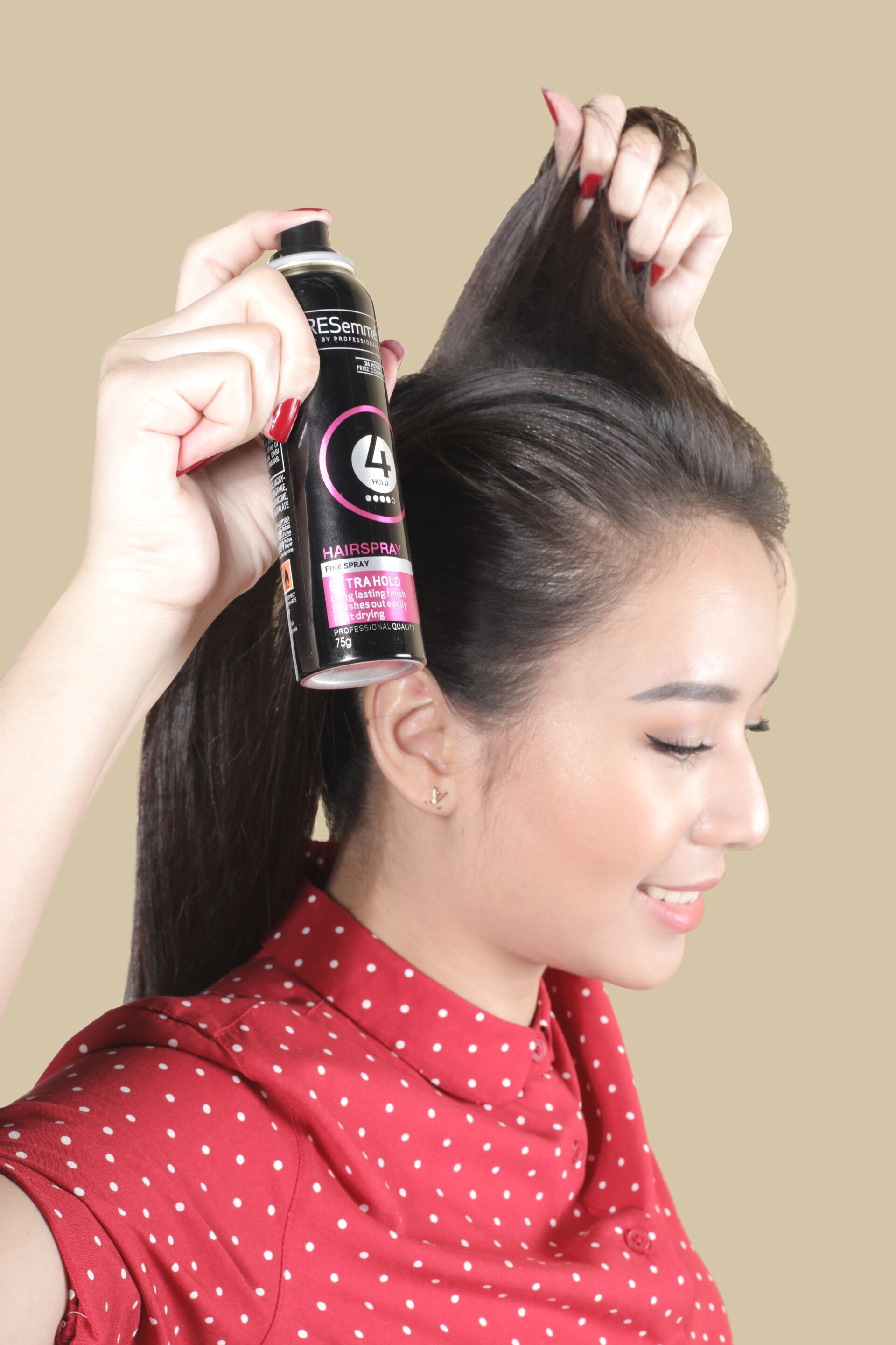 wanita asia sedang menata rambut dan menunjukkan hairspray