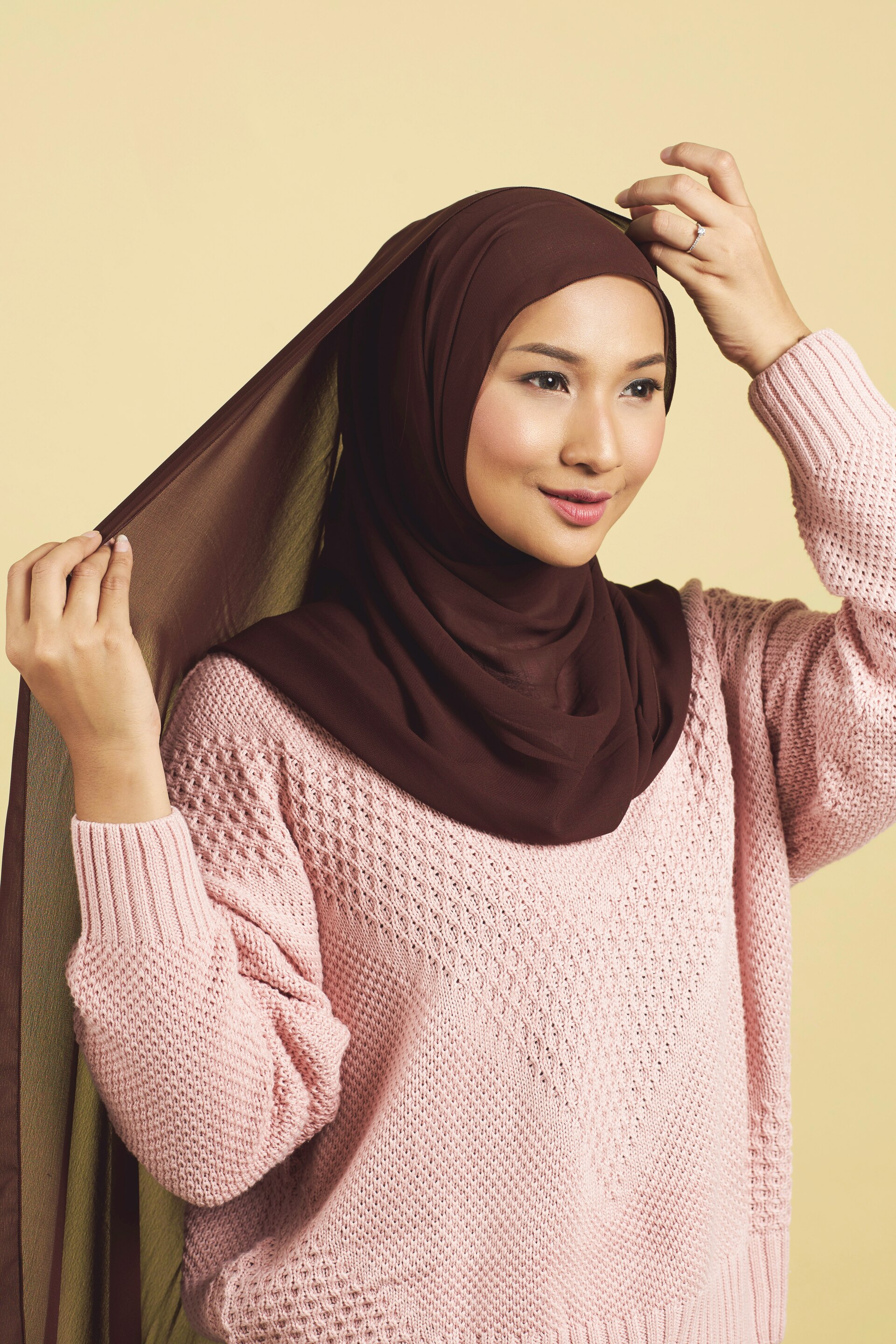 Wanita asia dengan hijab warna maroon dan sweater pink dalam gaya hijab arab
