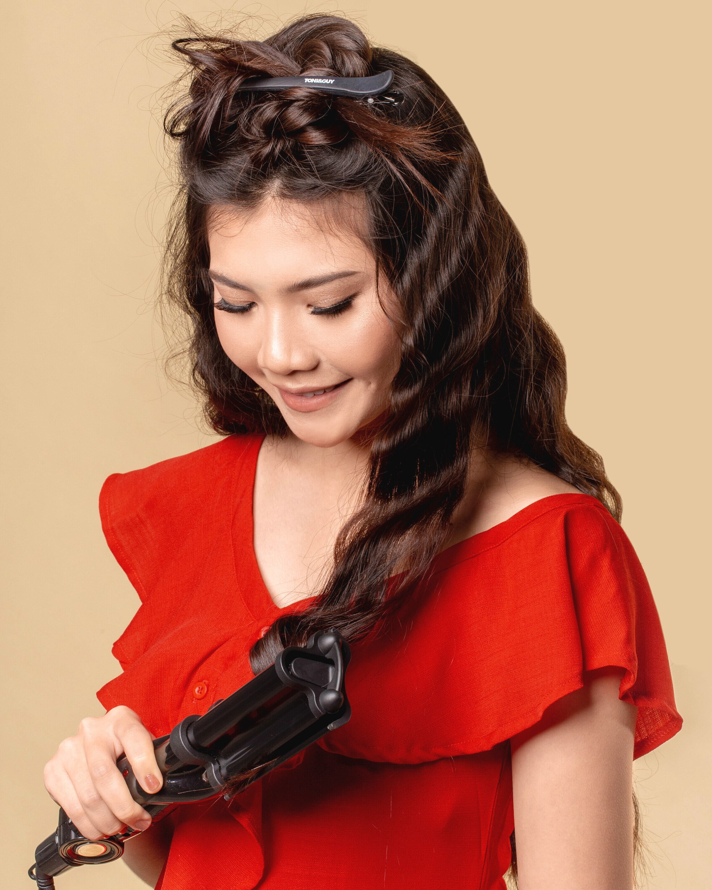 wanita asia sedang mengeriting rambut dengan catok