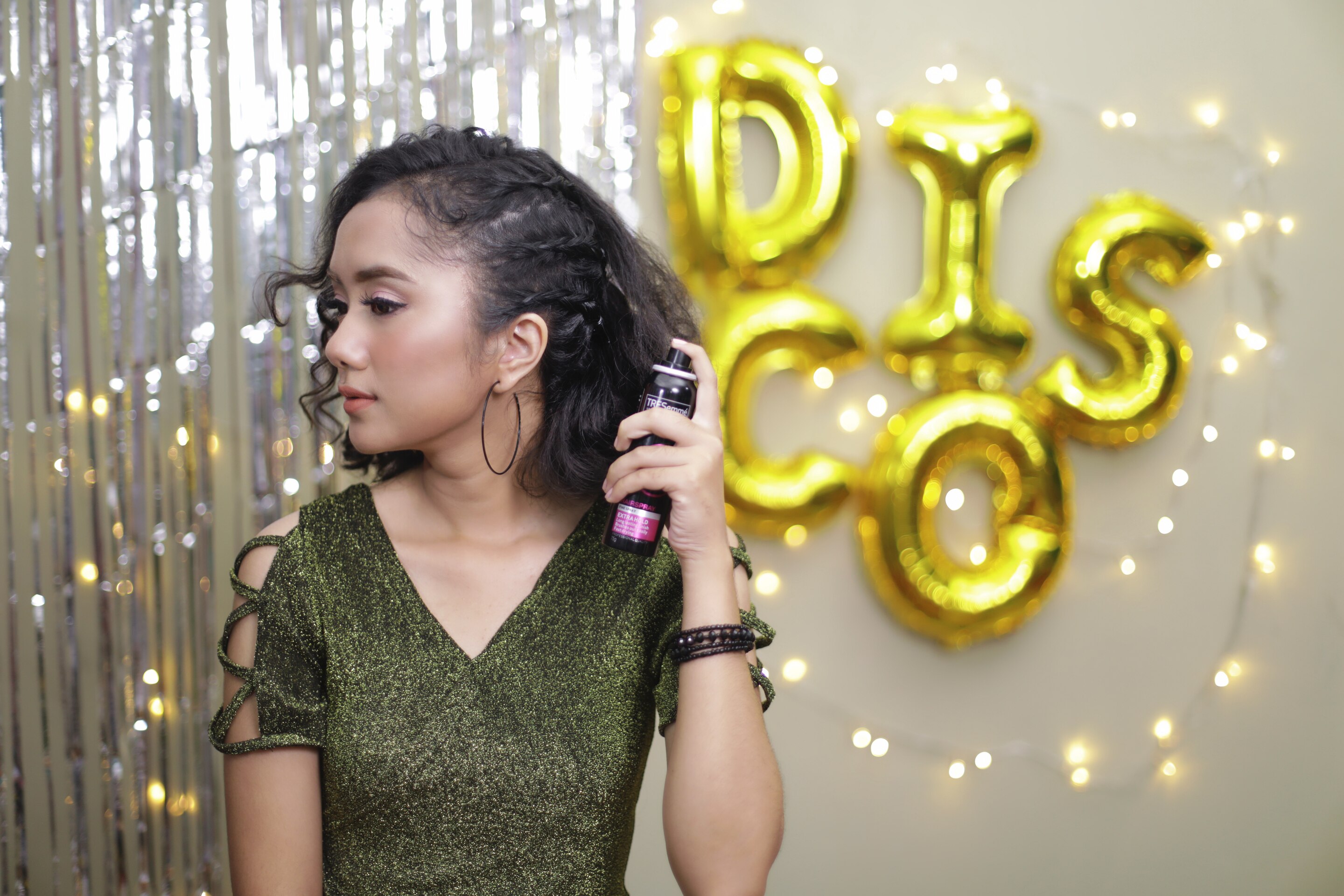 Wanita asia dengan rambut hitam keriting menyemprotkan hairspray pada rambut tebal dan keriting