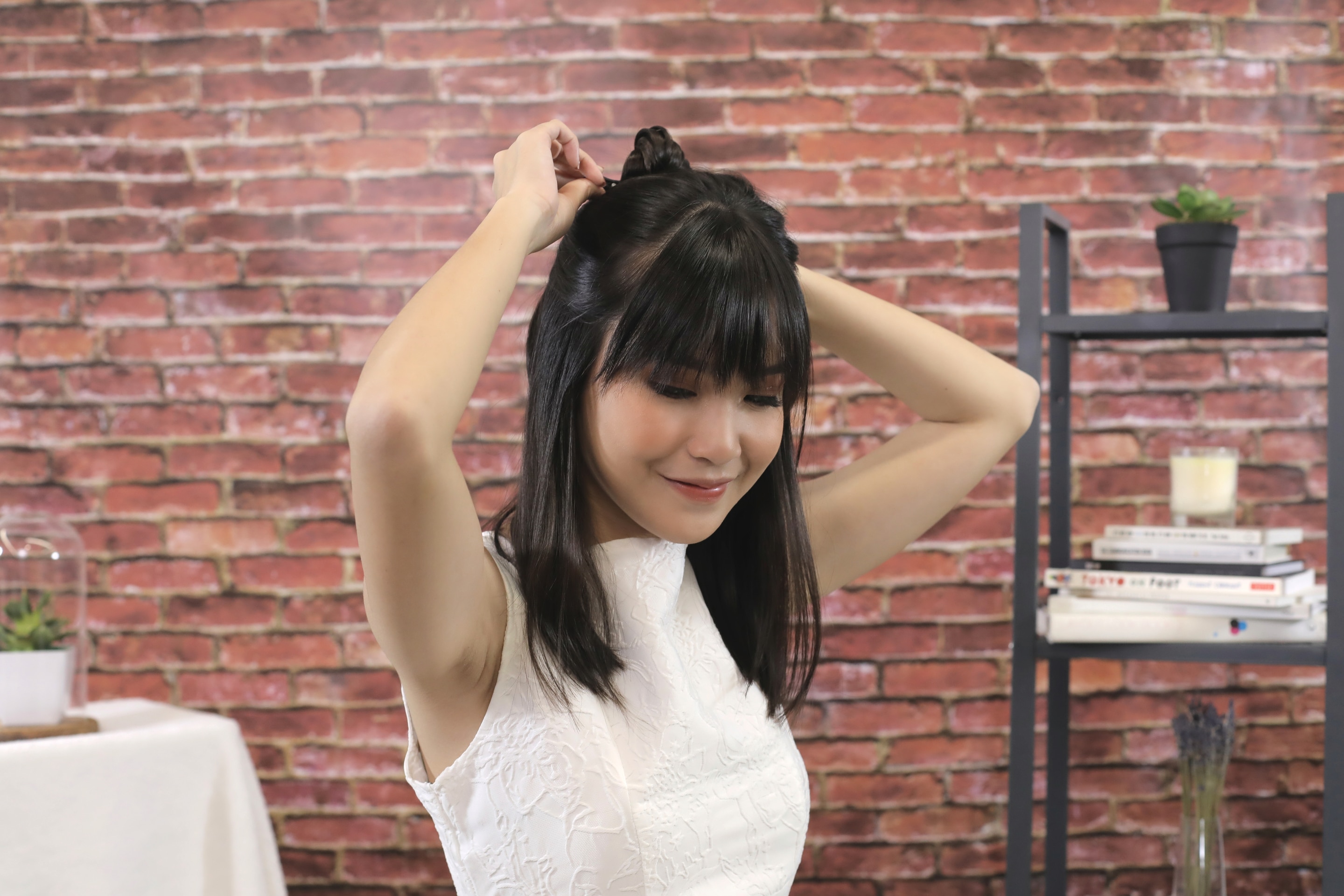 ผู้หญิงเอเชียผมยาวประบ่าสีดำ กำลังแบ่งผมครึ่งหัว