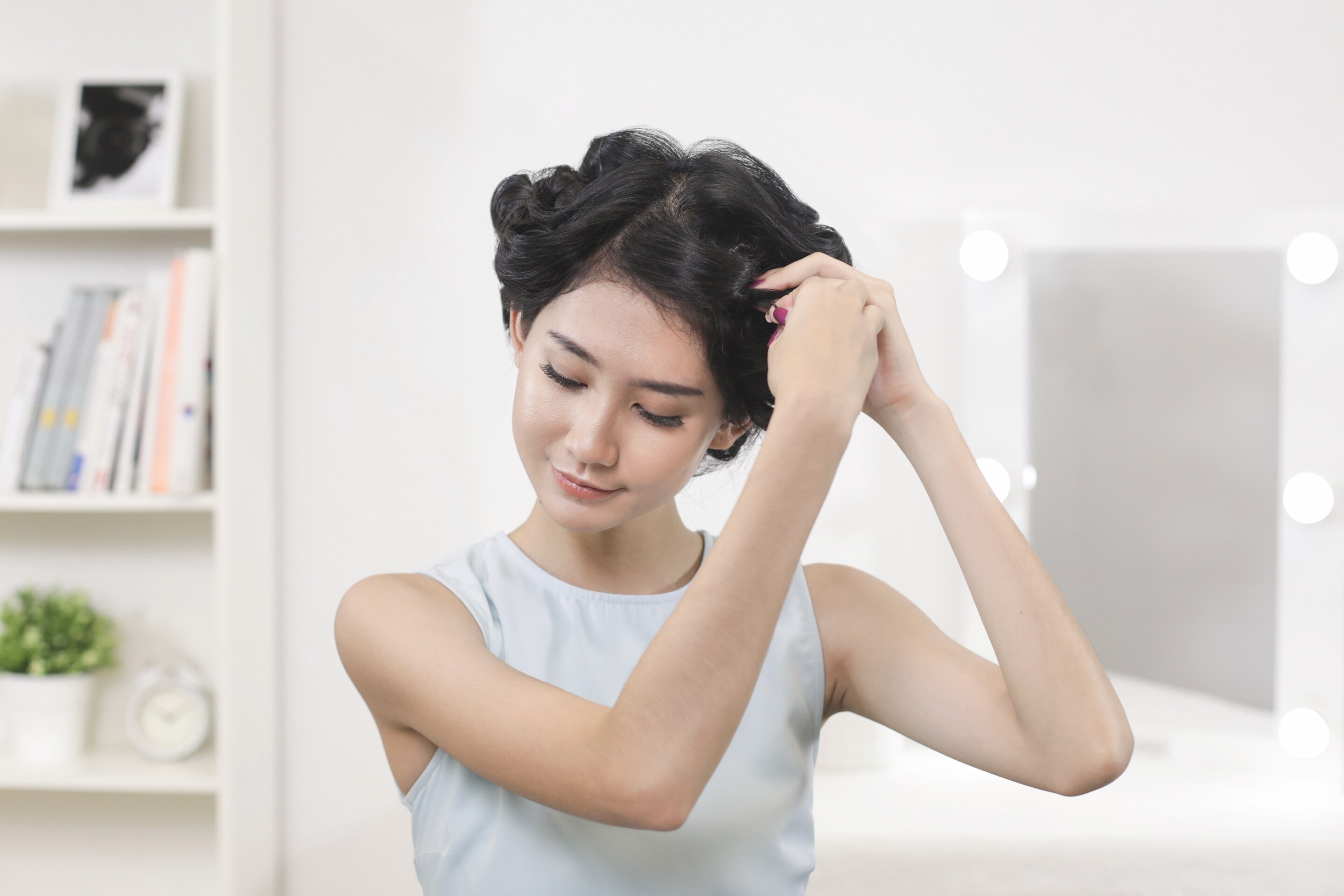 wanita asia sedang menjepit rambutnya dalam bentuk gulungan