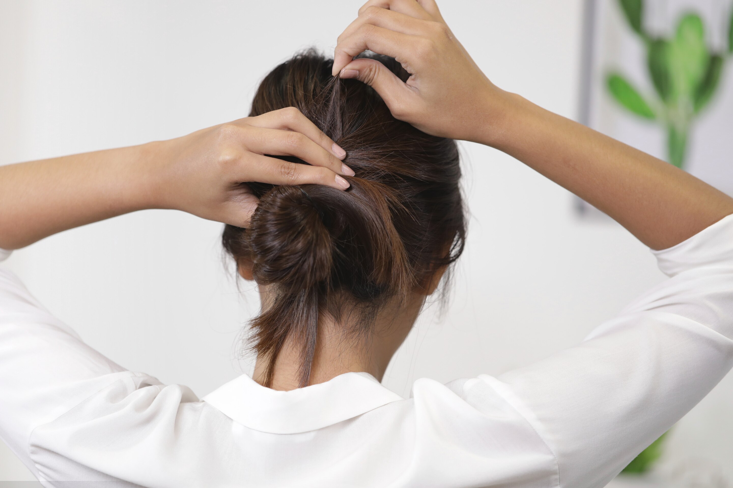 ผู้หญิงเอเชียผมยาวประบ่าสีดำ กำลังมัดผมบัน