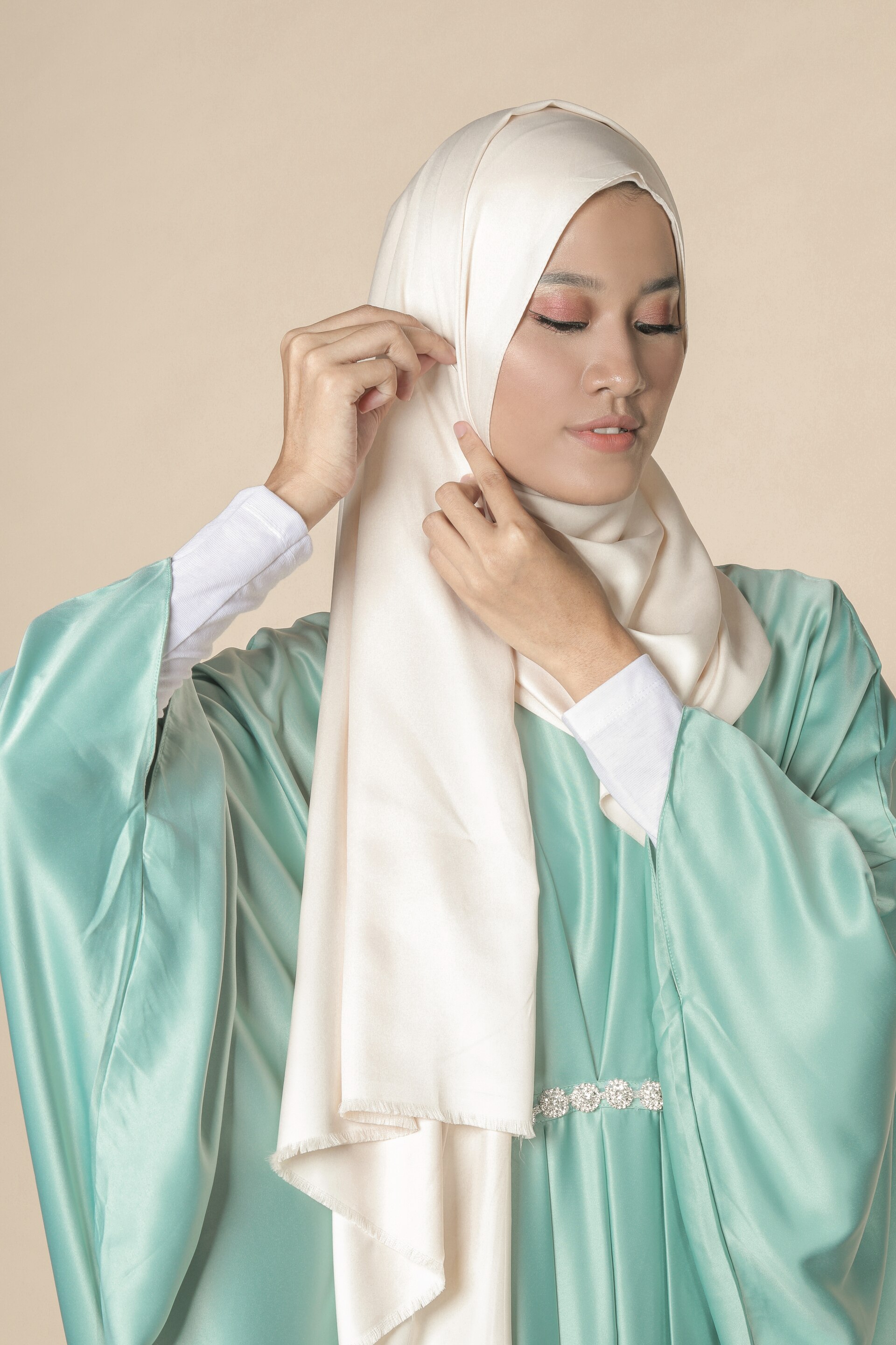 Wanita asia sedang menggunakan peniti untuk hijab panjang