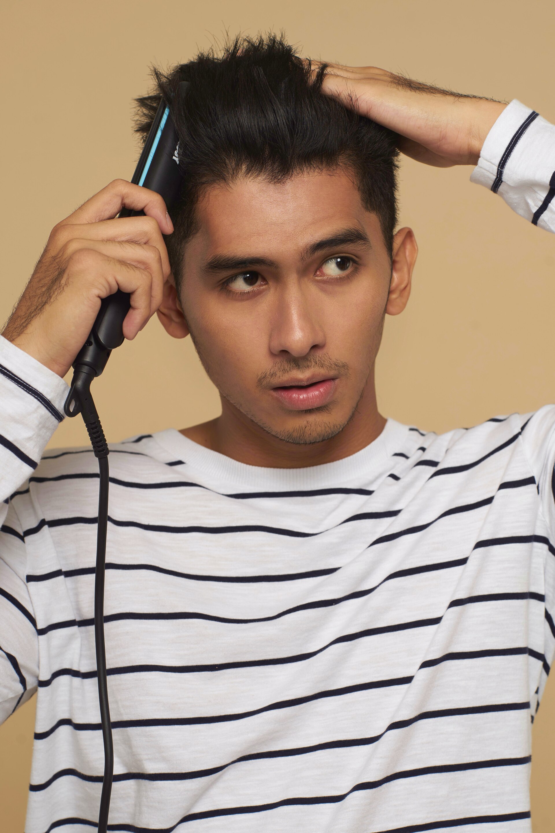 pria asia sedang menggunakan catokan atau flat iron