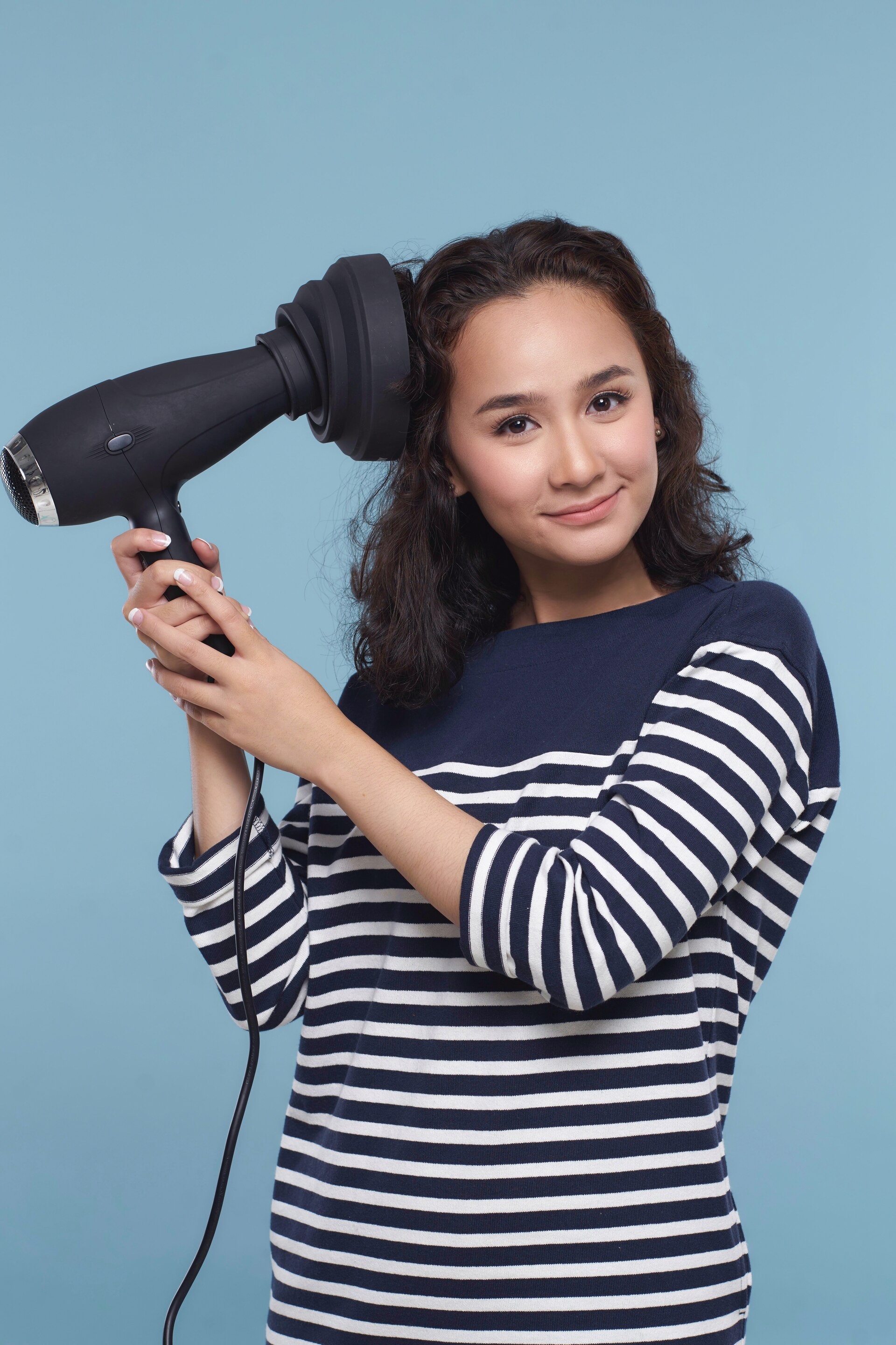 Wanita asia dengan rambut keriting pendek warna hitam mengeringkan akar rambut.