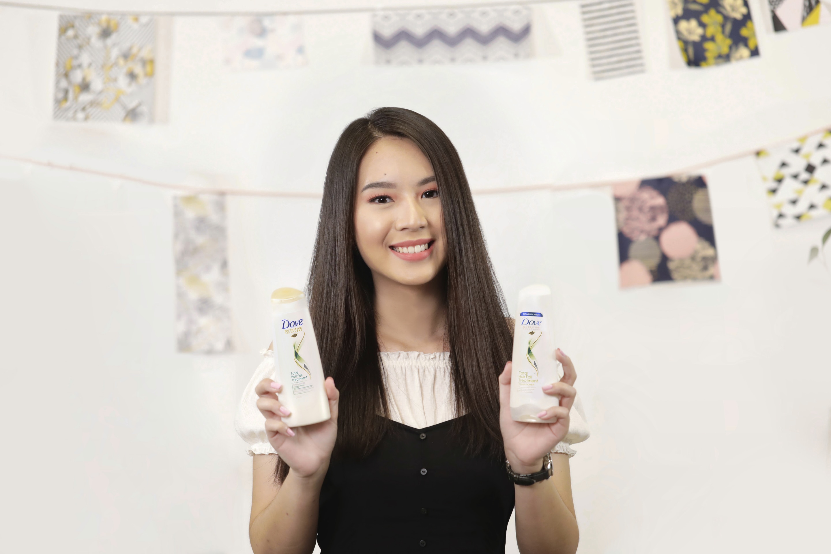 Wanita asia memegang botol shampoo dan conditioner