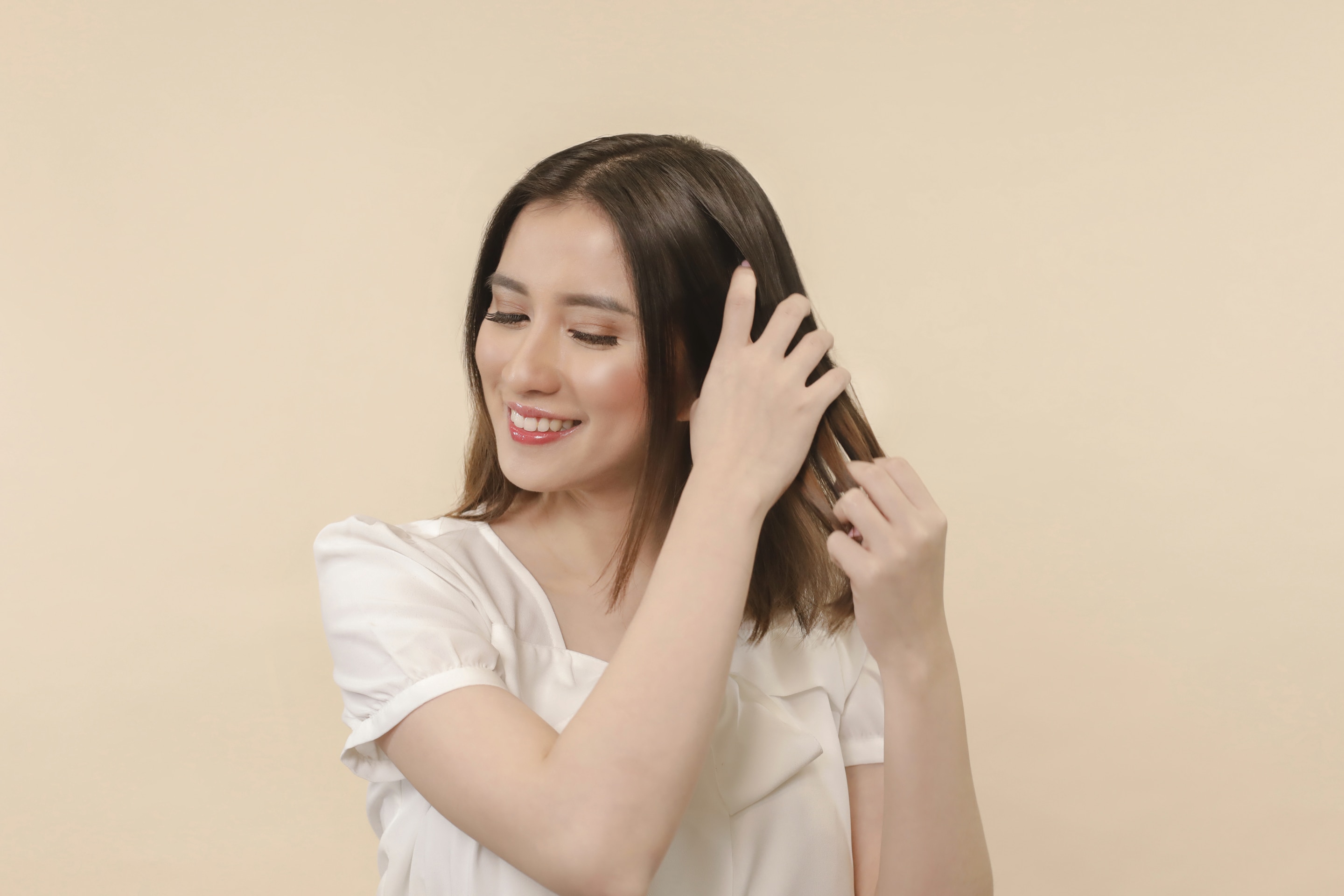 ผู้หญิงเอเชียผมสั้นสีดำ กำลังจับผม เตรียมทําผมบันยุ่งๆ