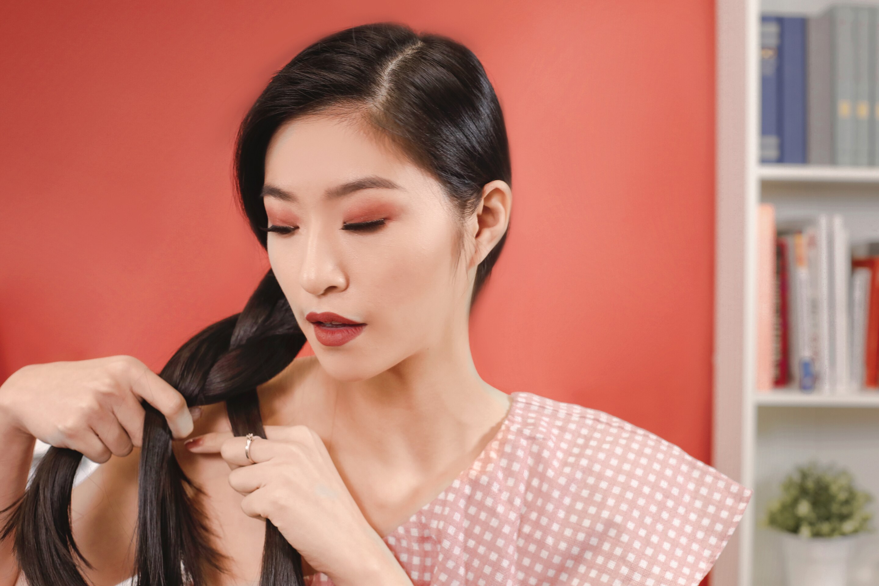 ผู้หญิงเอเชียผมยาวสีดำ กำลังถักเปียสาม