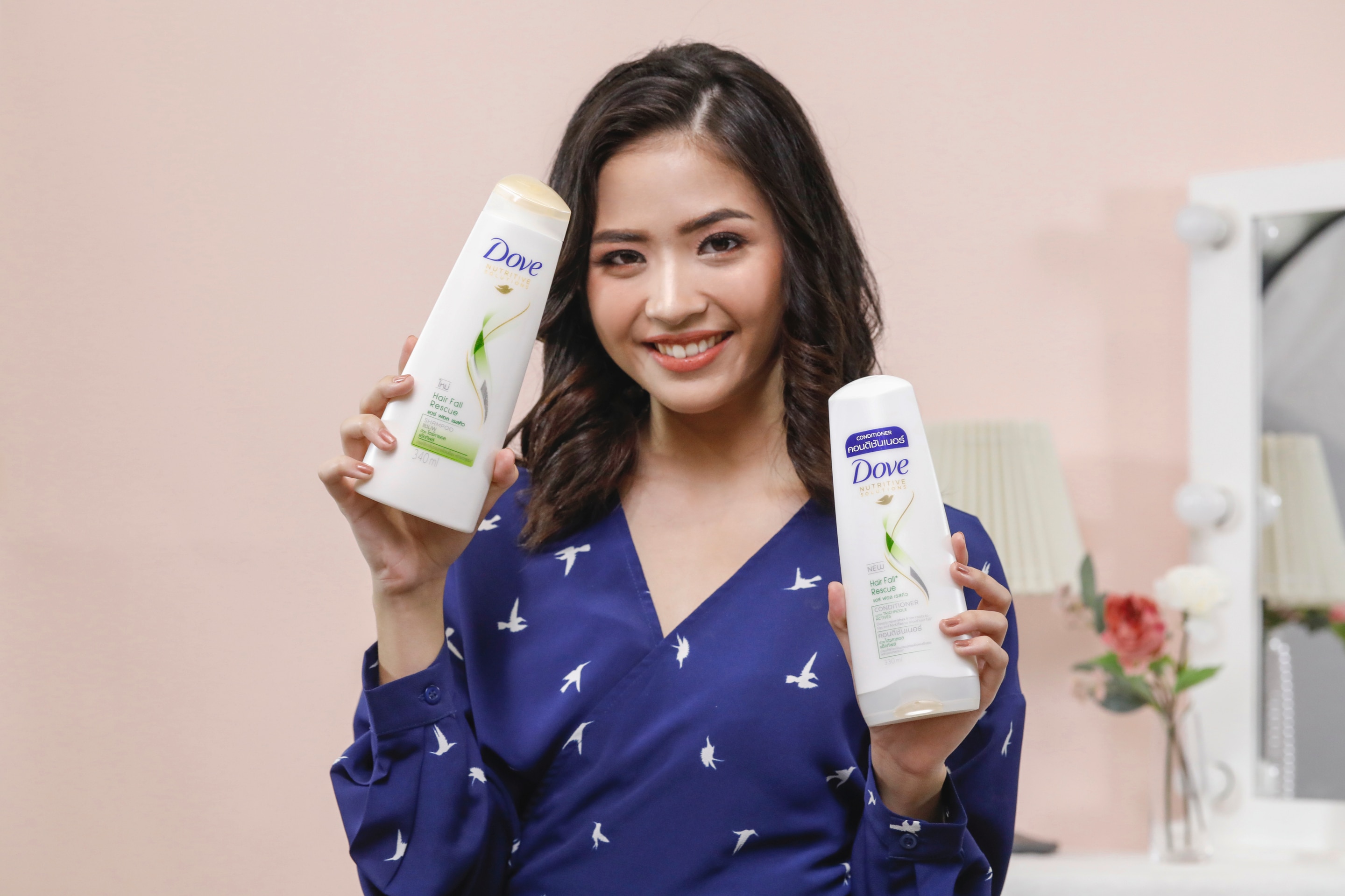 ผู้หญิงเอเชียผมยาวสีดำ กำลังถือขวดแชมพูและครีมนวดผม