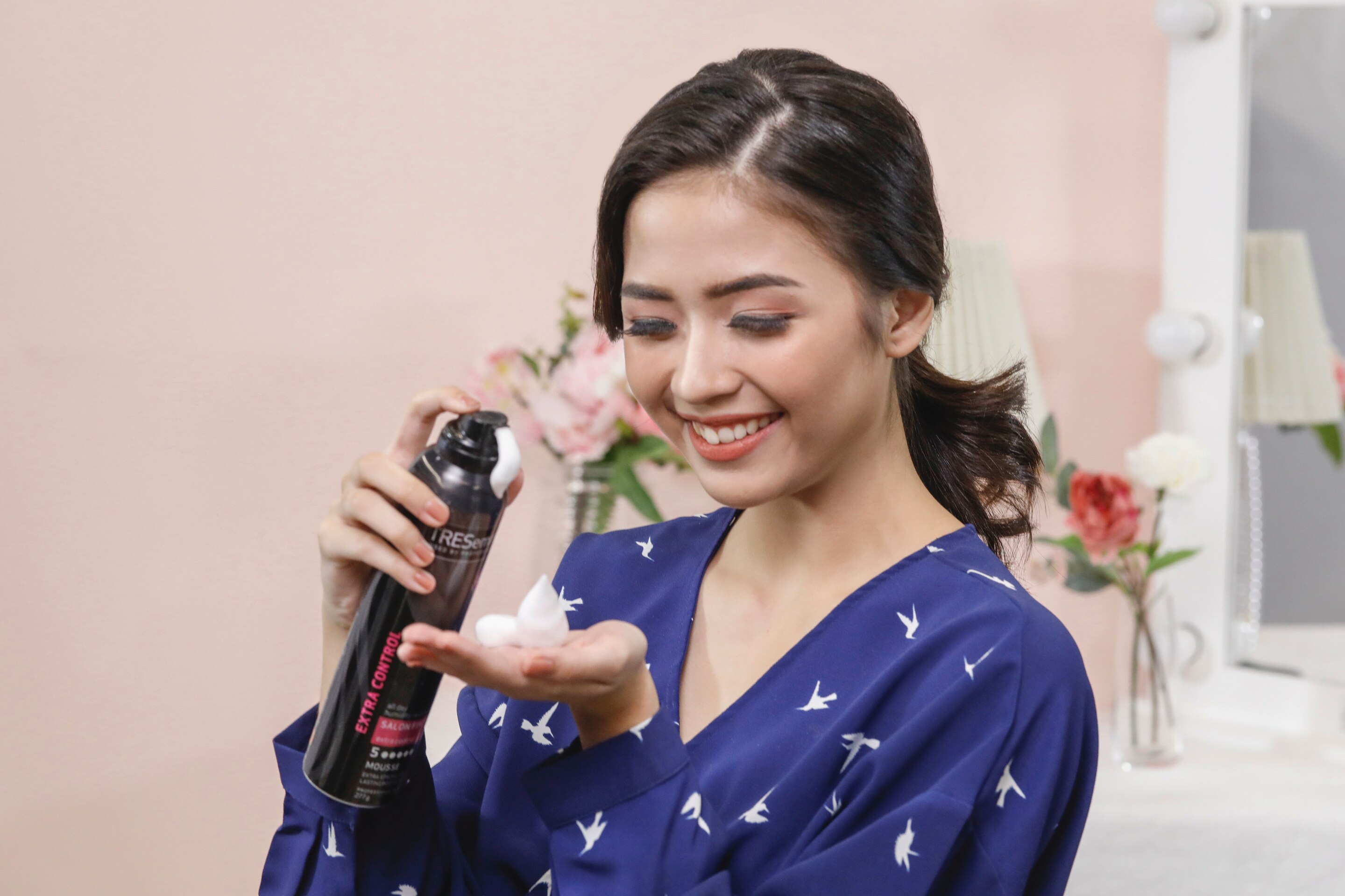 ผู้หญิงเอเชียผมยาวสีดำ กำลังบีบมูสลงบนฝ่ามือ