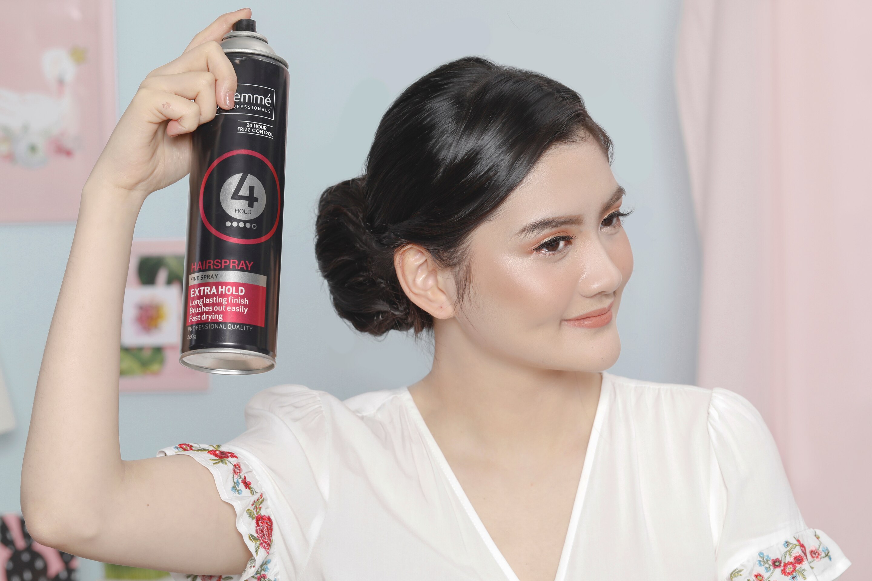 Wanita dengan rambut panjang menyemprotkan sanggul twist