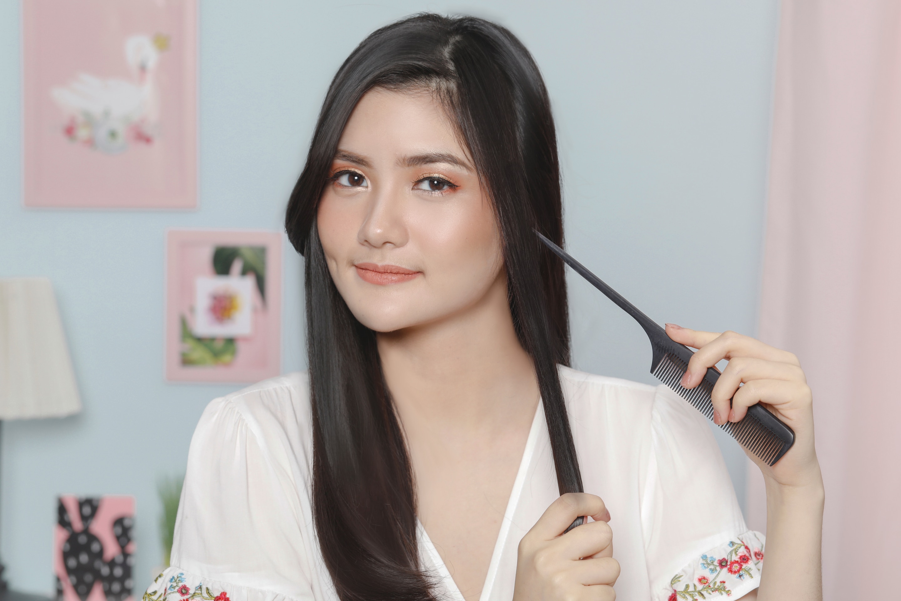 ผู้หญิงเอเชียผมยาวสีดำ กำลังใช้หวีหางแบ่งผม