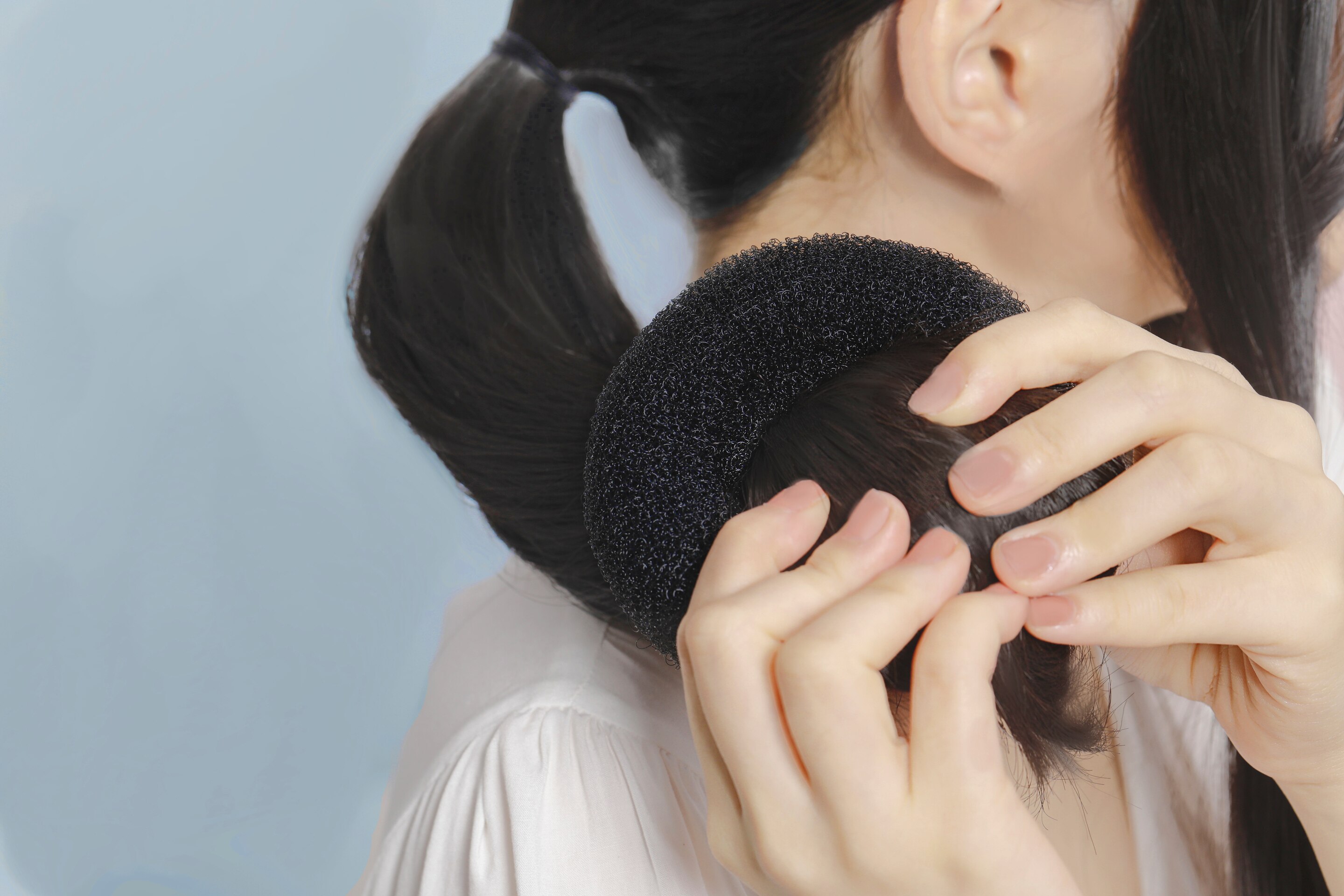 Wanita asia sedang menggulung rambut dengan donut untuk membuat sanggul