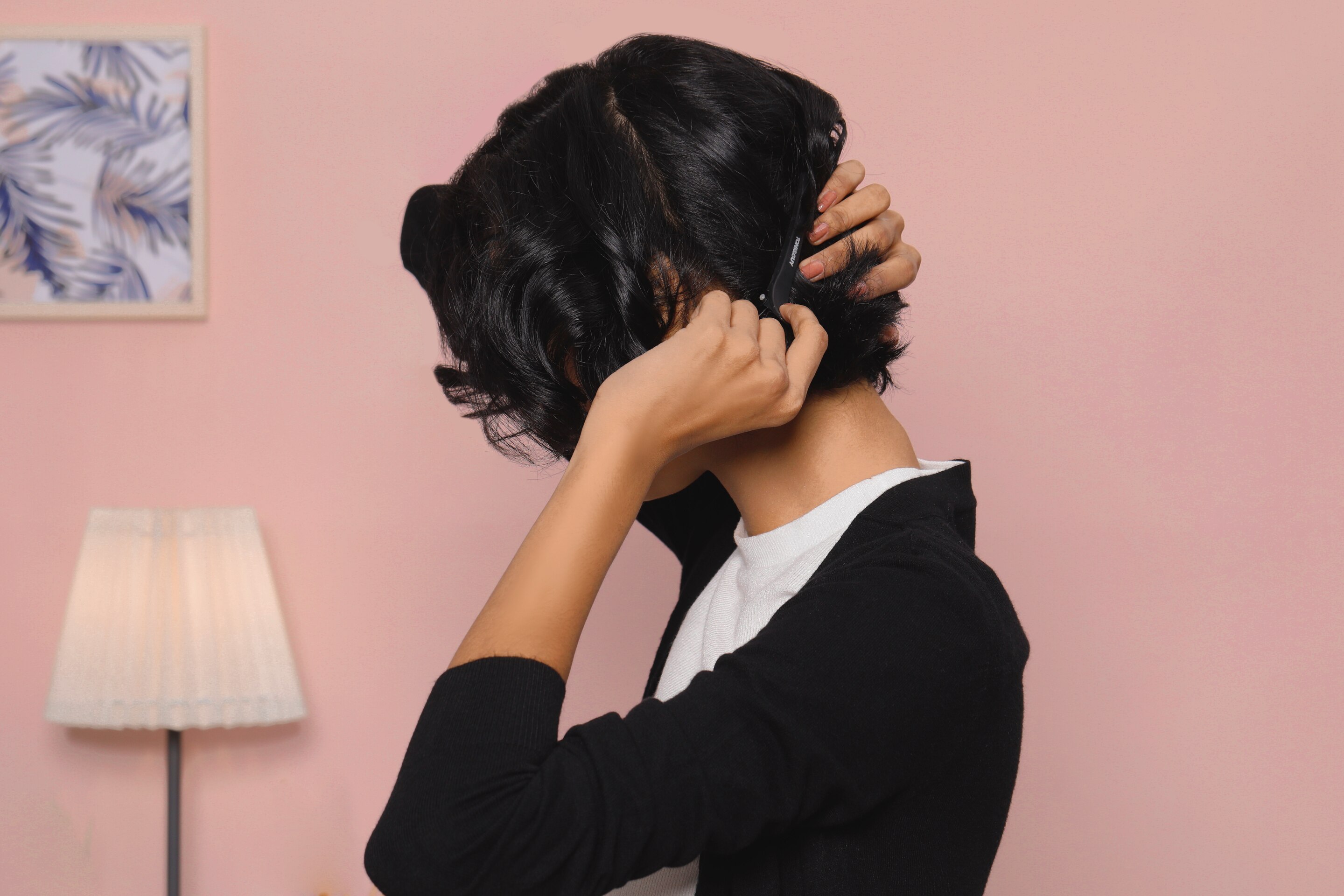 ผู้หญิงเอเชีย ผมหยิกสั้น กำลังใช้กิ๊บหนีบแบ่งผม