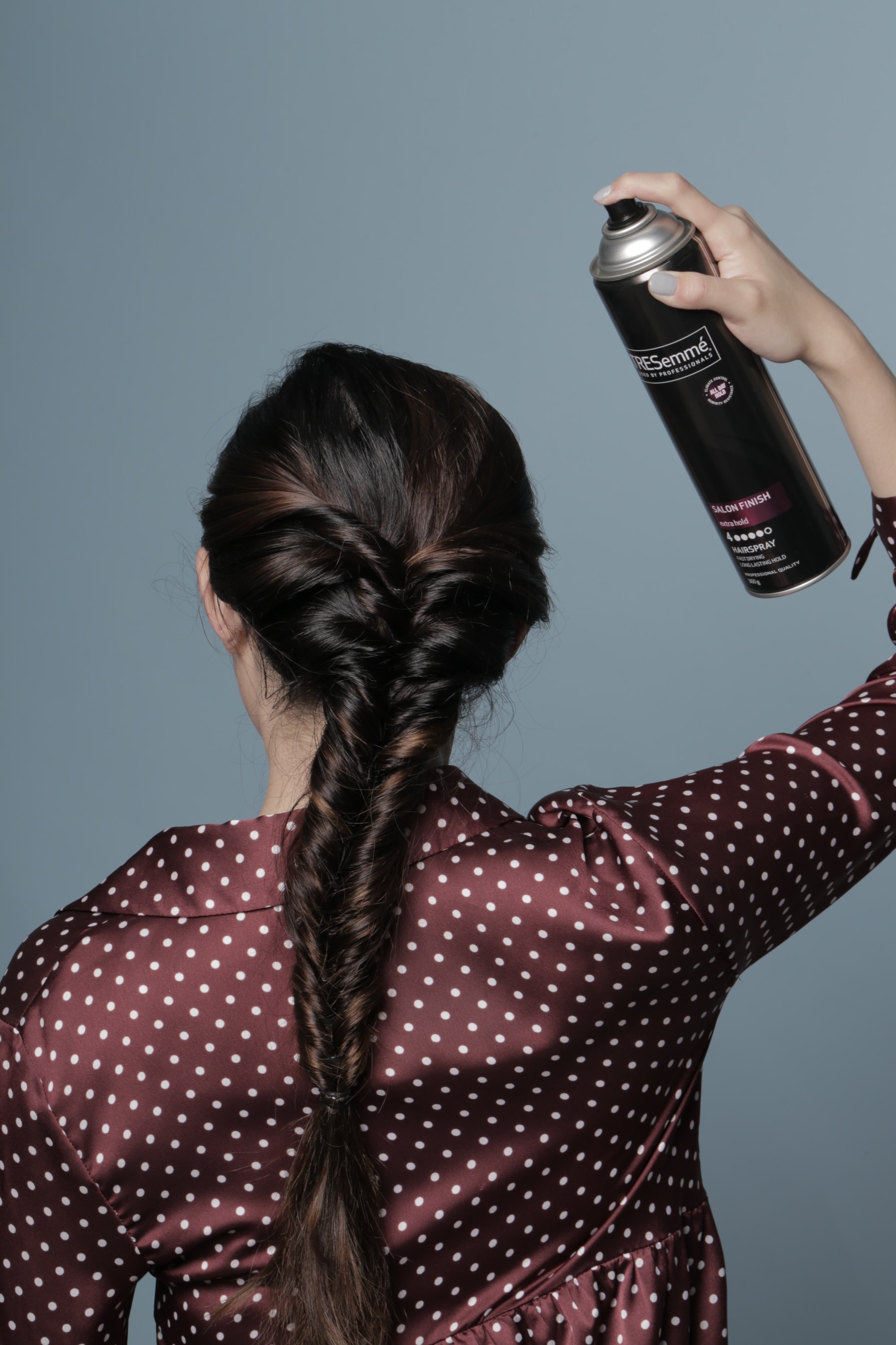Wanita asia dengan rambut cokelat menyemprotkan hairspray ke rambut - bohemian faux braid