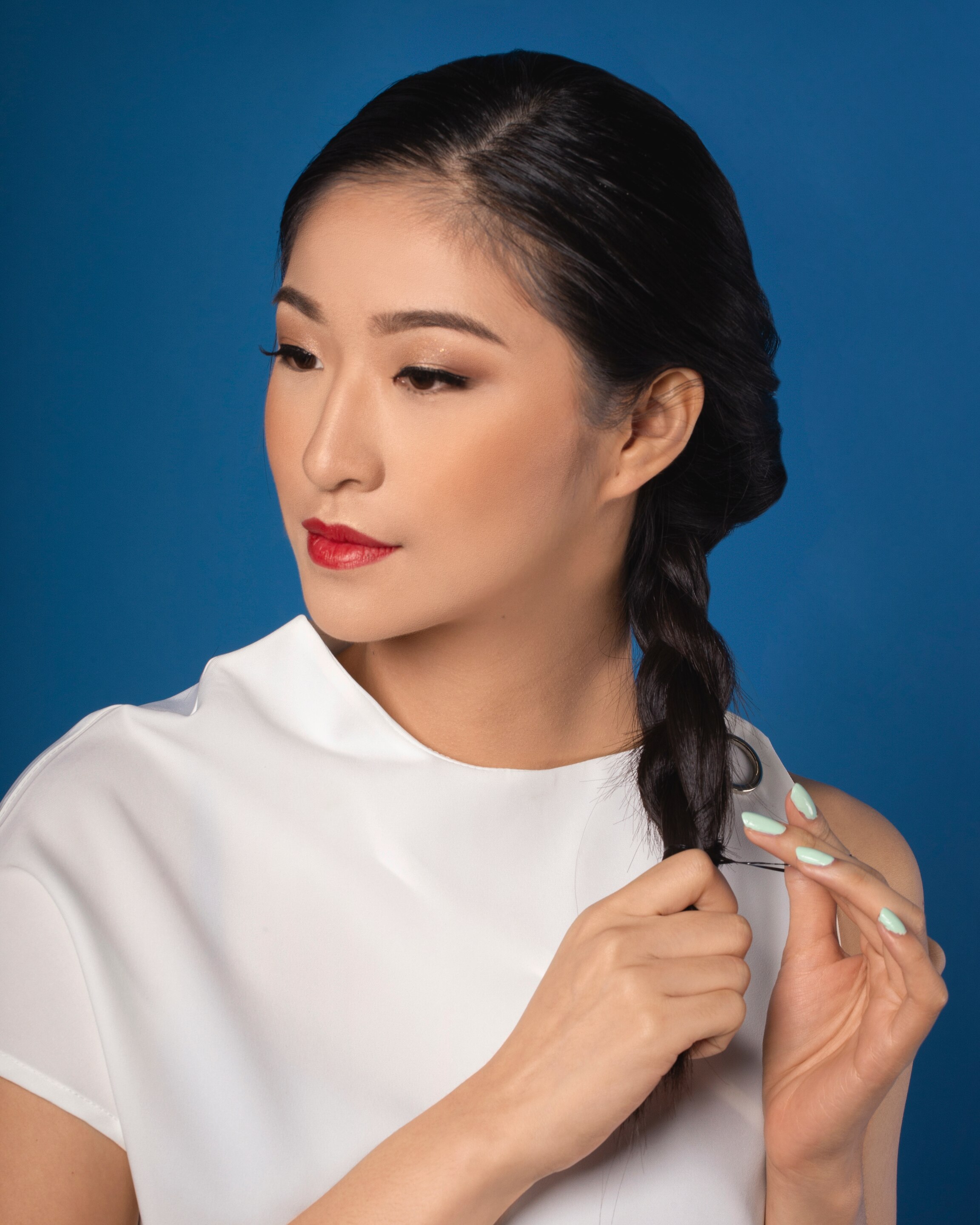 wanita asia dengan baju putih menata rambutnya dengan gaya sanggul kepang lilit