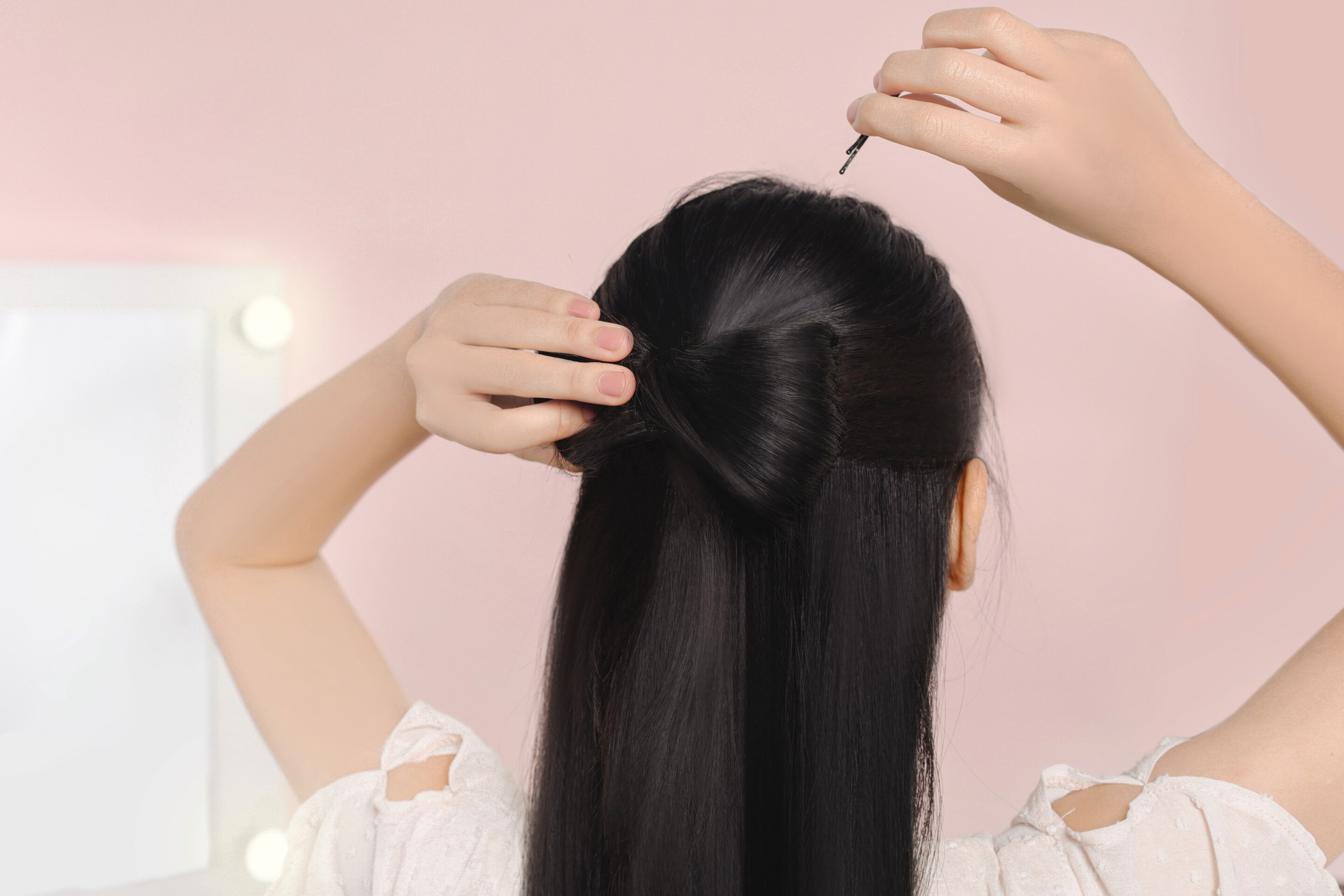 ผู้หญิงหันหลัง ผมยาวสีดำ กำลังติดกี๊บ ทำผมเป็นรูปโบว์