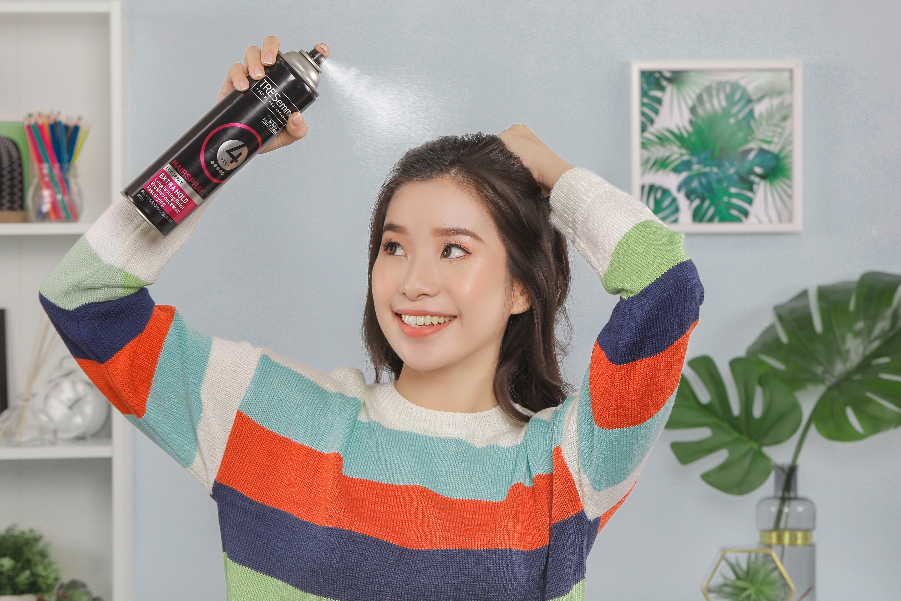 ผู้หญิงเอเชียผมยาวสีดำ กำลังฉีดสเปรย์แต่งผม