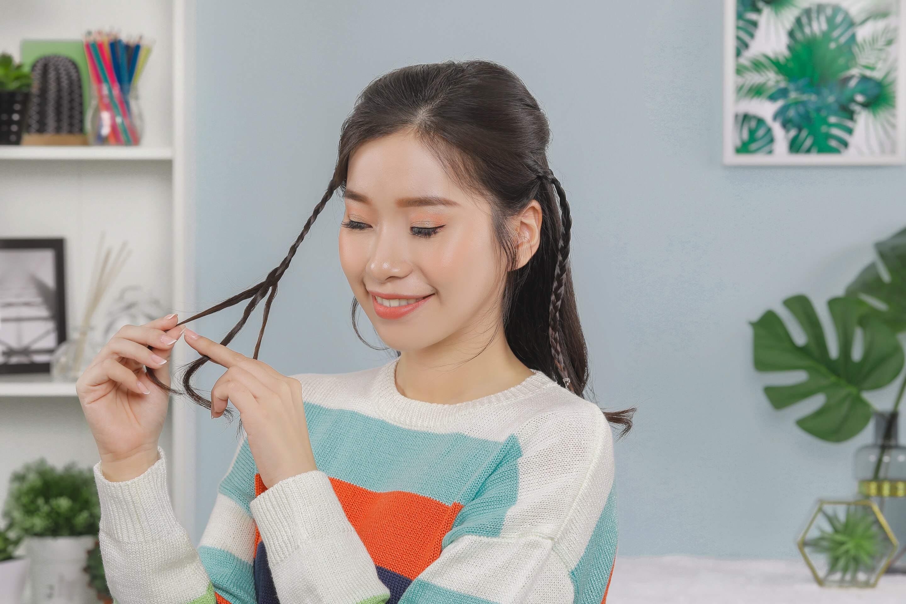 ผู้หญิงเอเชียผมยาวสีดำ กำลังถักเปียเส้นเล็กๆ