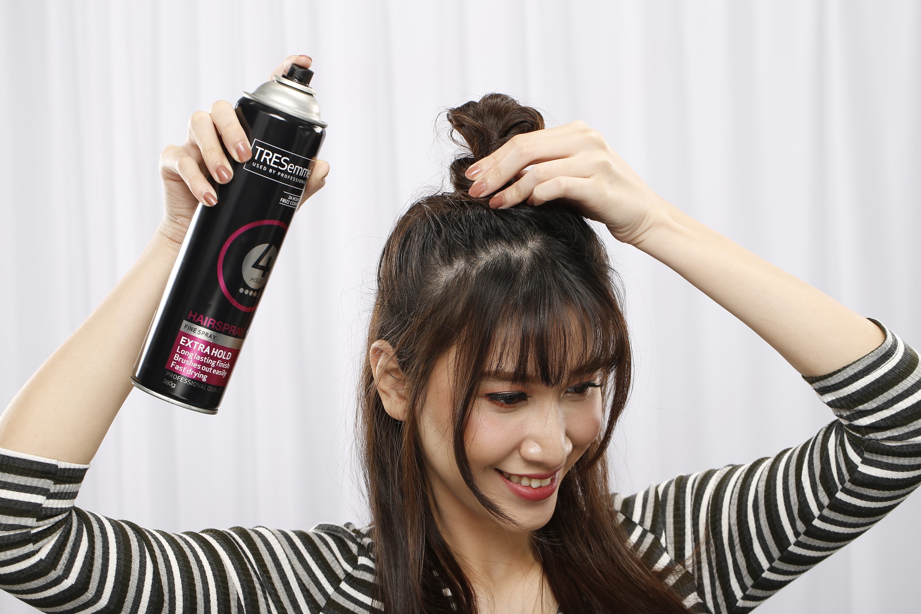 ผู้หญิงเอเชียผมยาวสีดำ กำลังฉีดสเปรย์แต่งผม