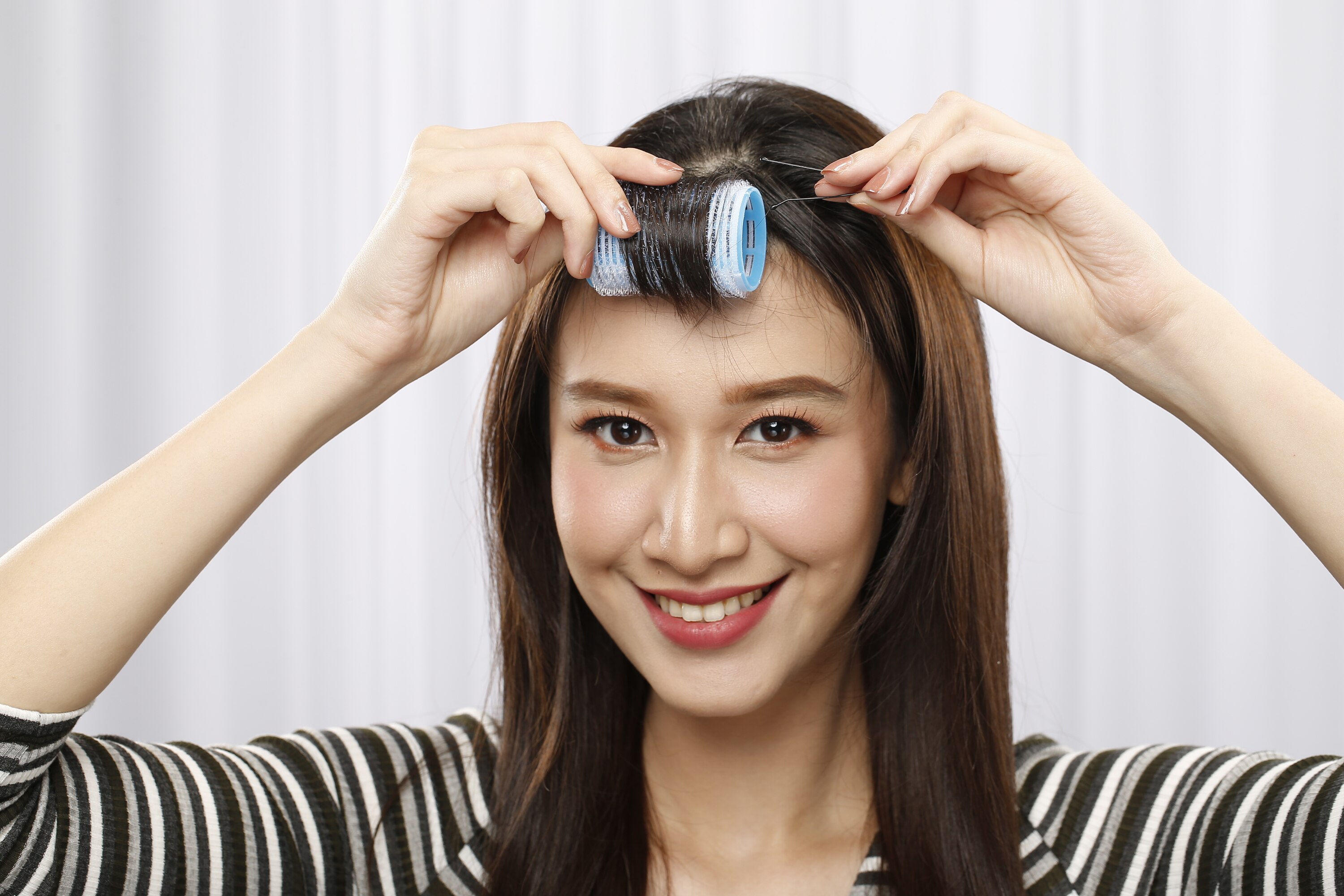 ผู้หญิงเอเชียผมยาวสีดำ เอาโรลมาม้วนผมหน้าม้า