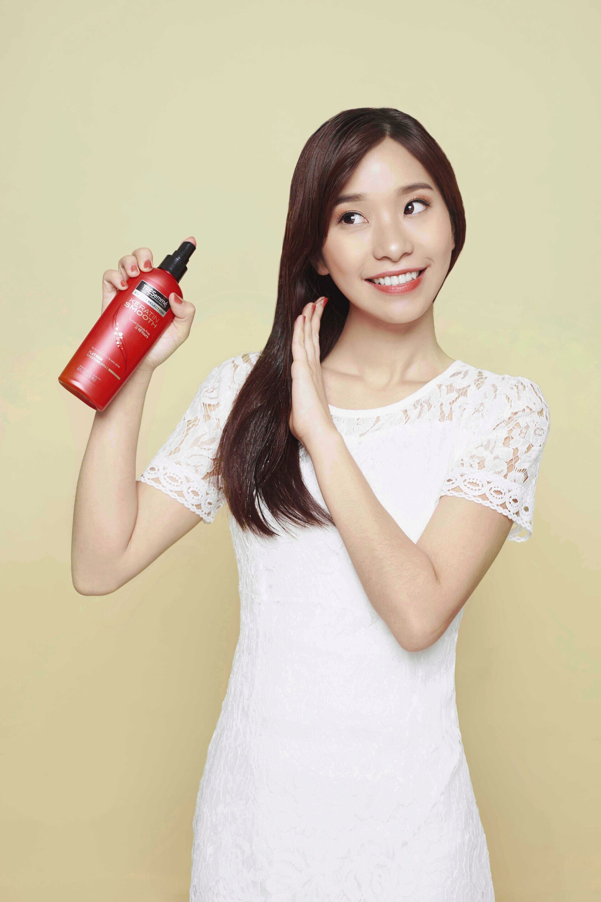 Wanita asia dengan rambut hitam menggunakan TRESemmé Keratin Smooth Flat Iron Smoothing Spray