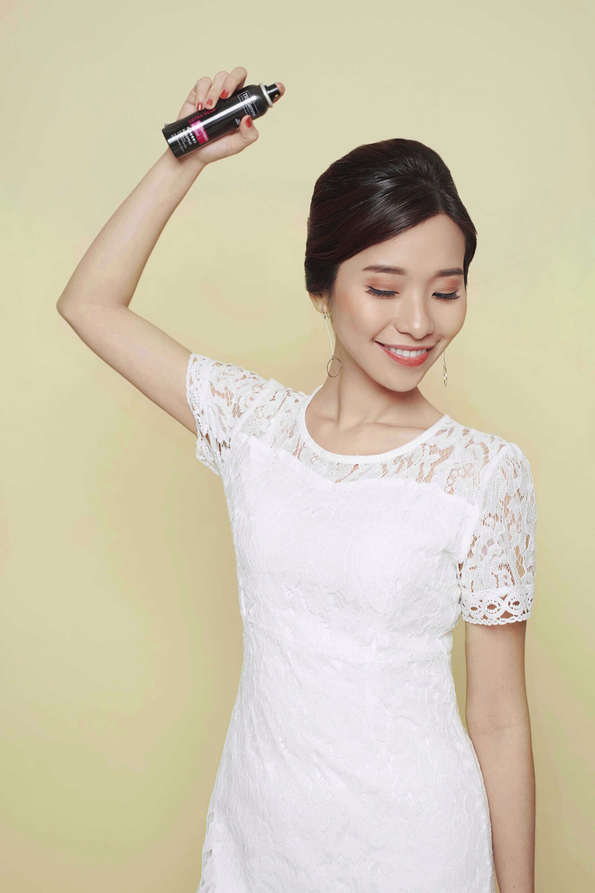 Wanita asia dengan rambut hitam sanggul French twist menggunakan hair spray