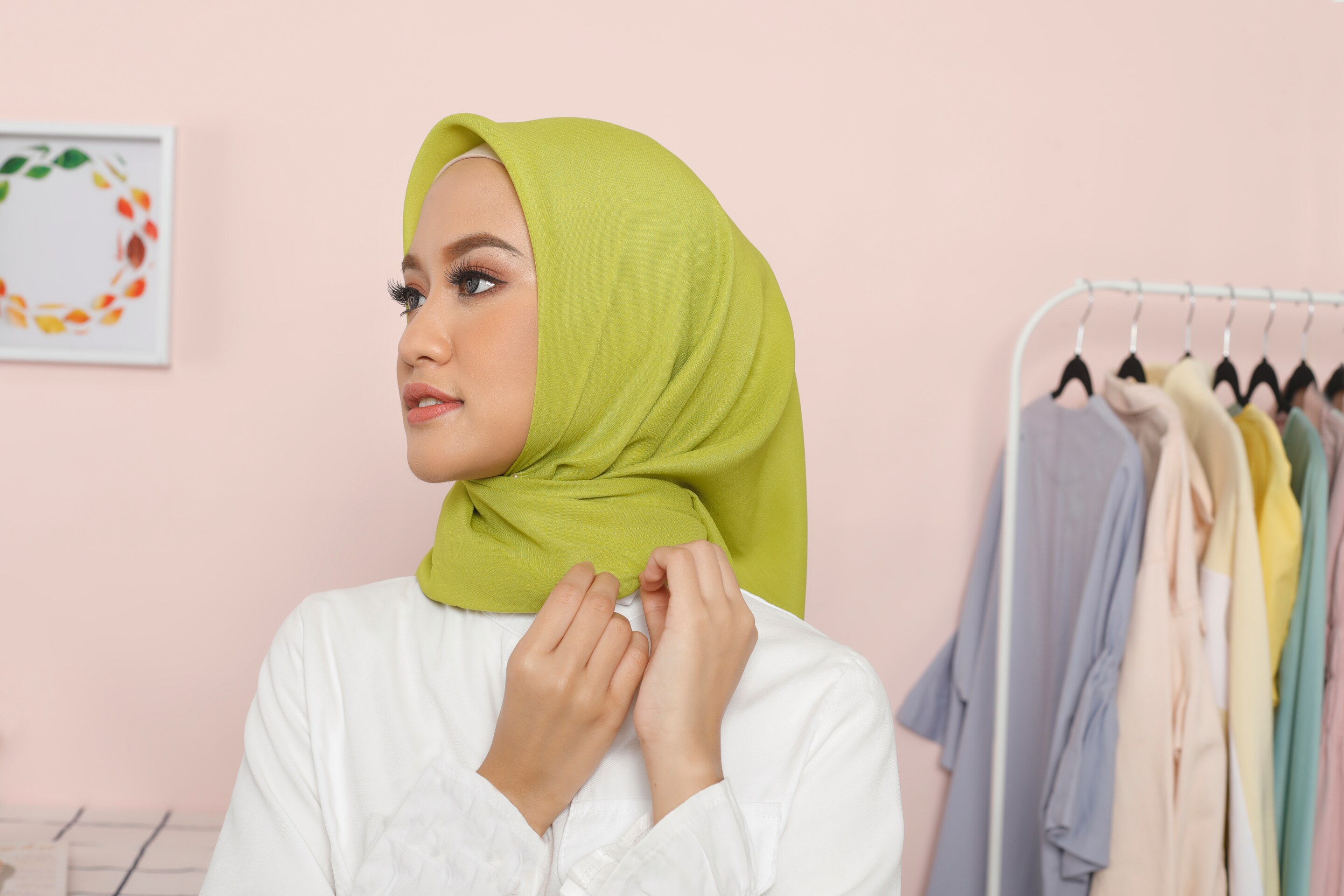 Wanita Asia merapikan hijab segi empat di kamarnya.