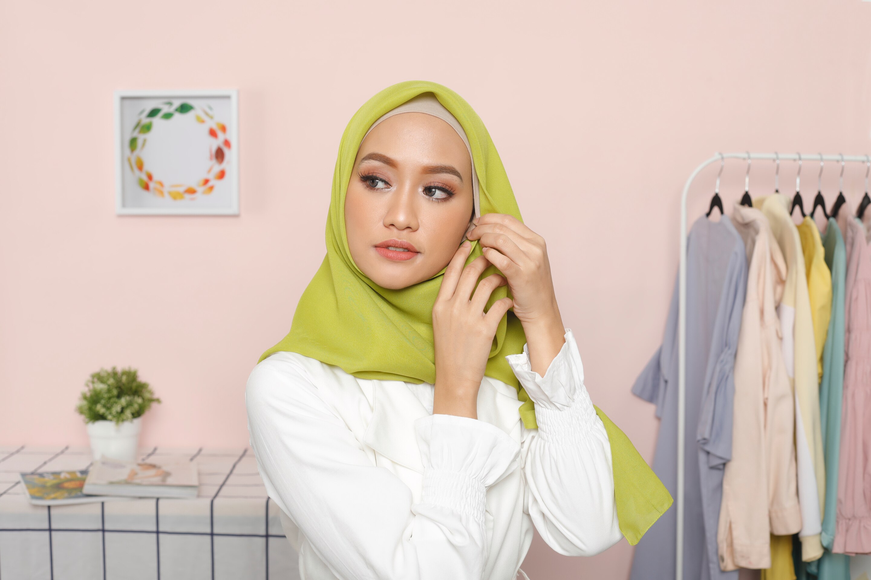 Wanita Asia memasangkan jarum pentul di bagian kanan hijabnya.