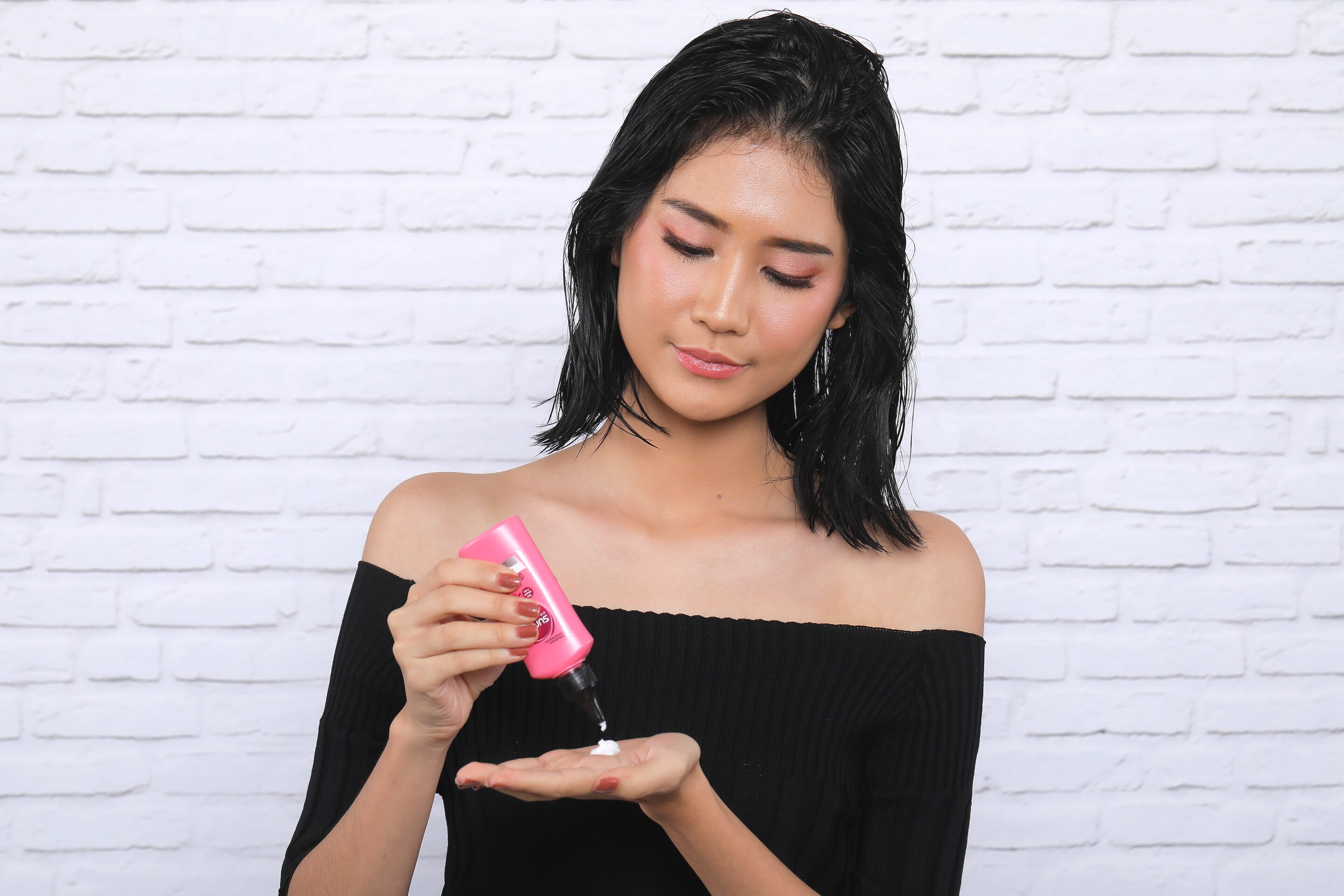 ผู้หญิงเอเชียผมสั้นกำลังบีบลีฟออนลงบนฝ่ามือ สาธิต วิธีเกล้าผมสั้น