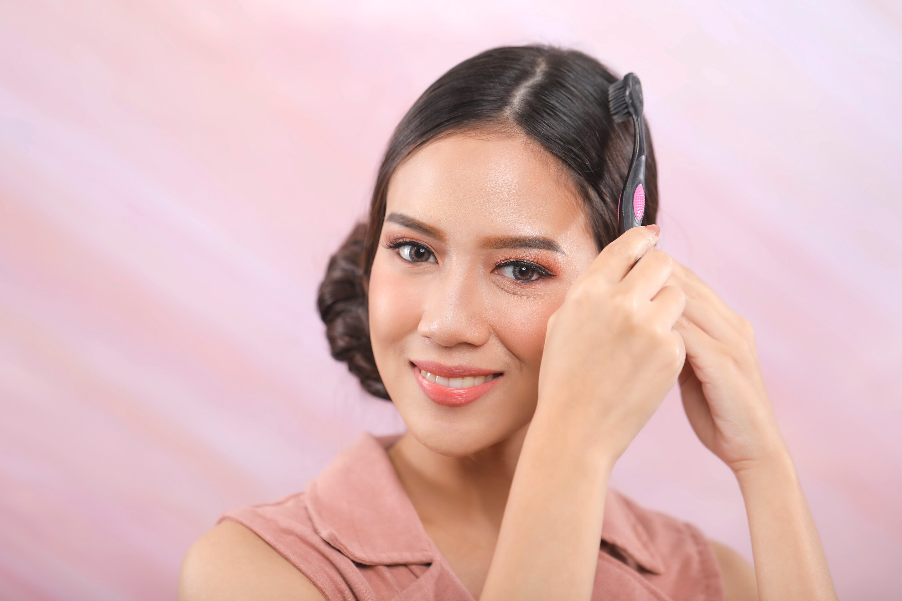 Wanita asia menyemprotkan hairspray pada sikat gigi