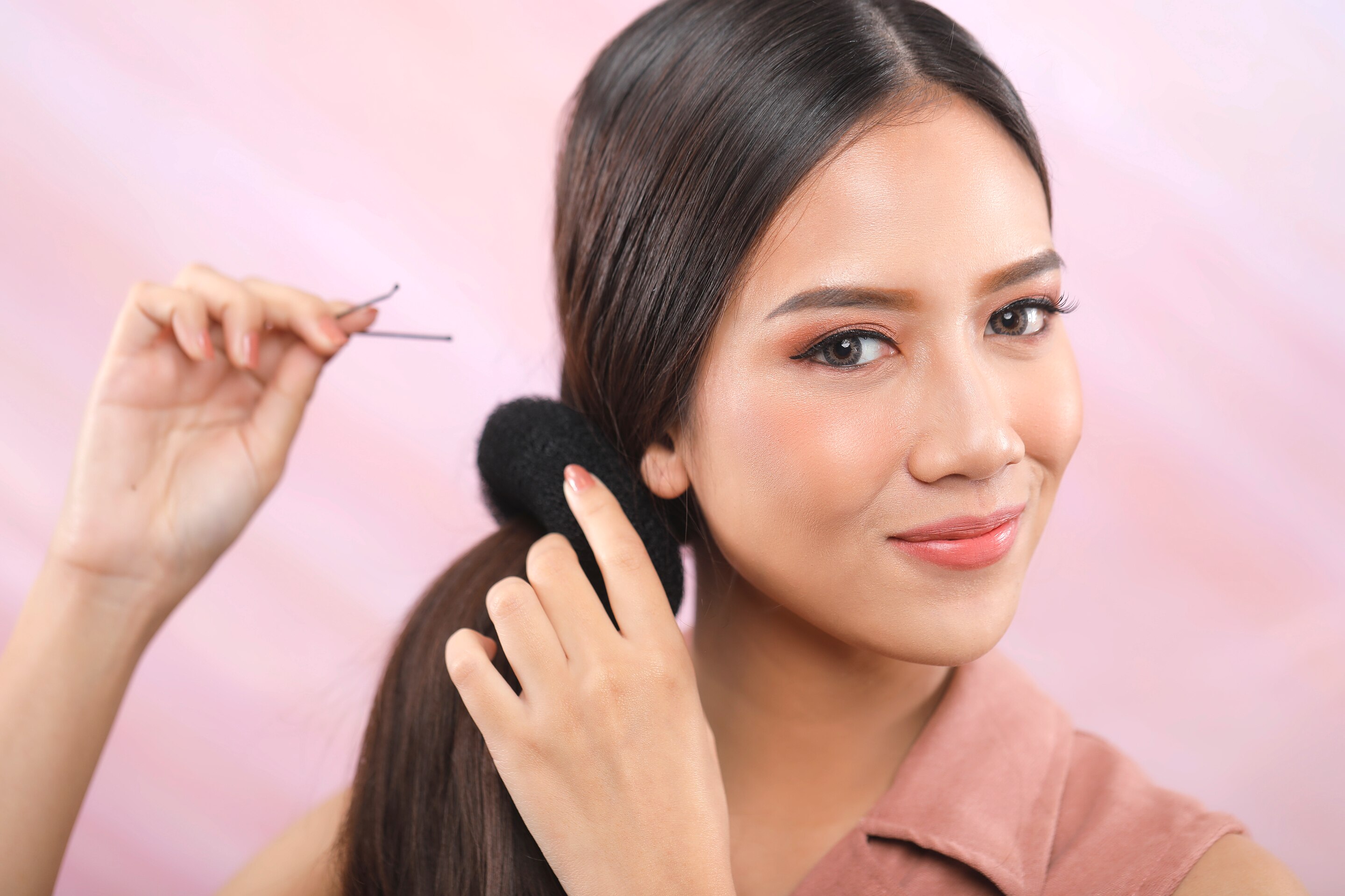 Wanita asia menata rambut dengan donat rambut