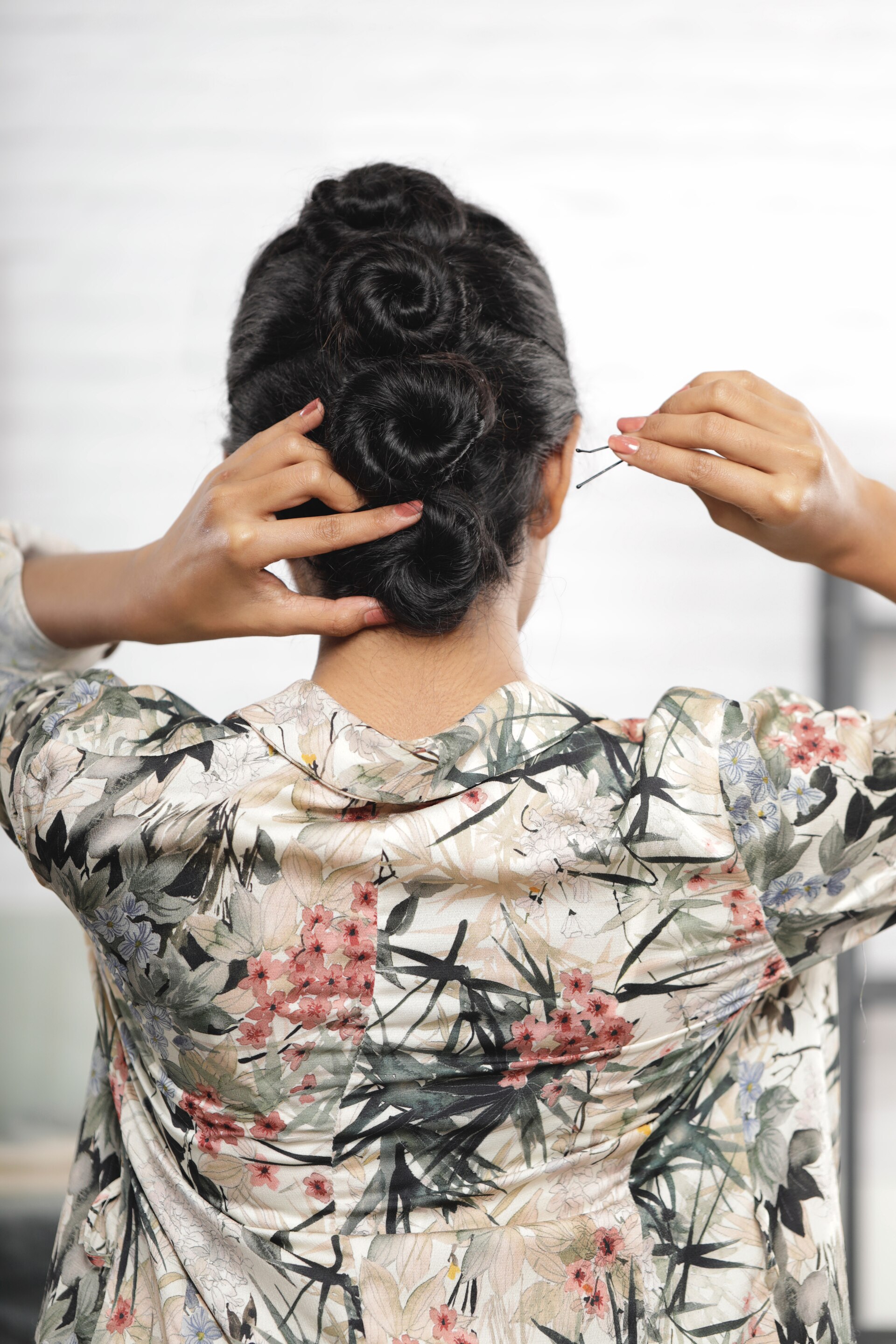 ผู้หญิงเอเชีย ไว้ผมยาวหยิก สีดำ กำลังรวบผมขึ้นด้านบนและติดกิ๊บ