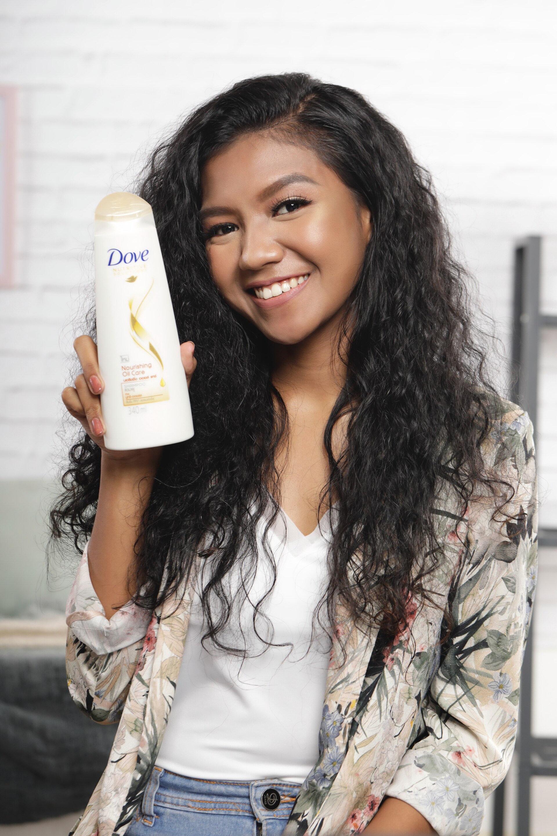 ผู้หญิงเอเชีย ไว้ผมยาวหยิก สีดำ ถือขวดแชมพูโดฟ