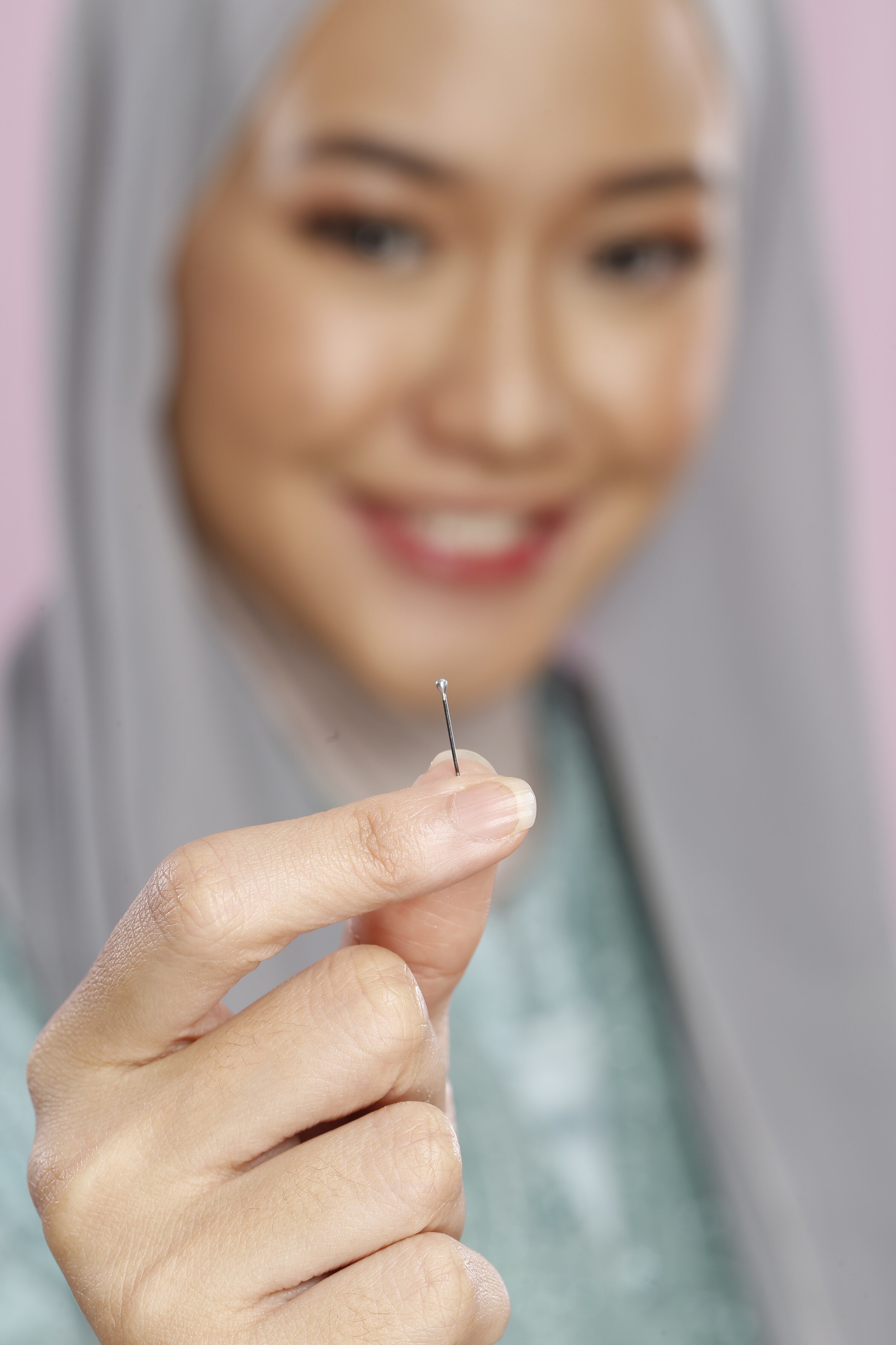 Wanita berhijab memperlihatkan jarum pentul paku