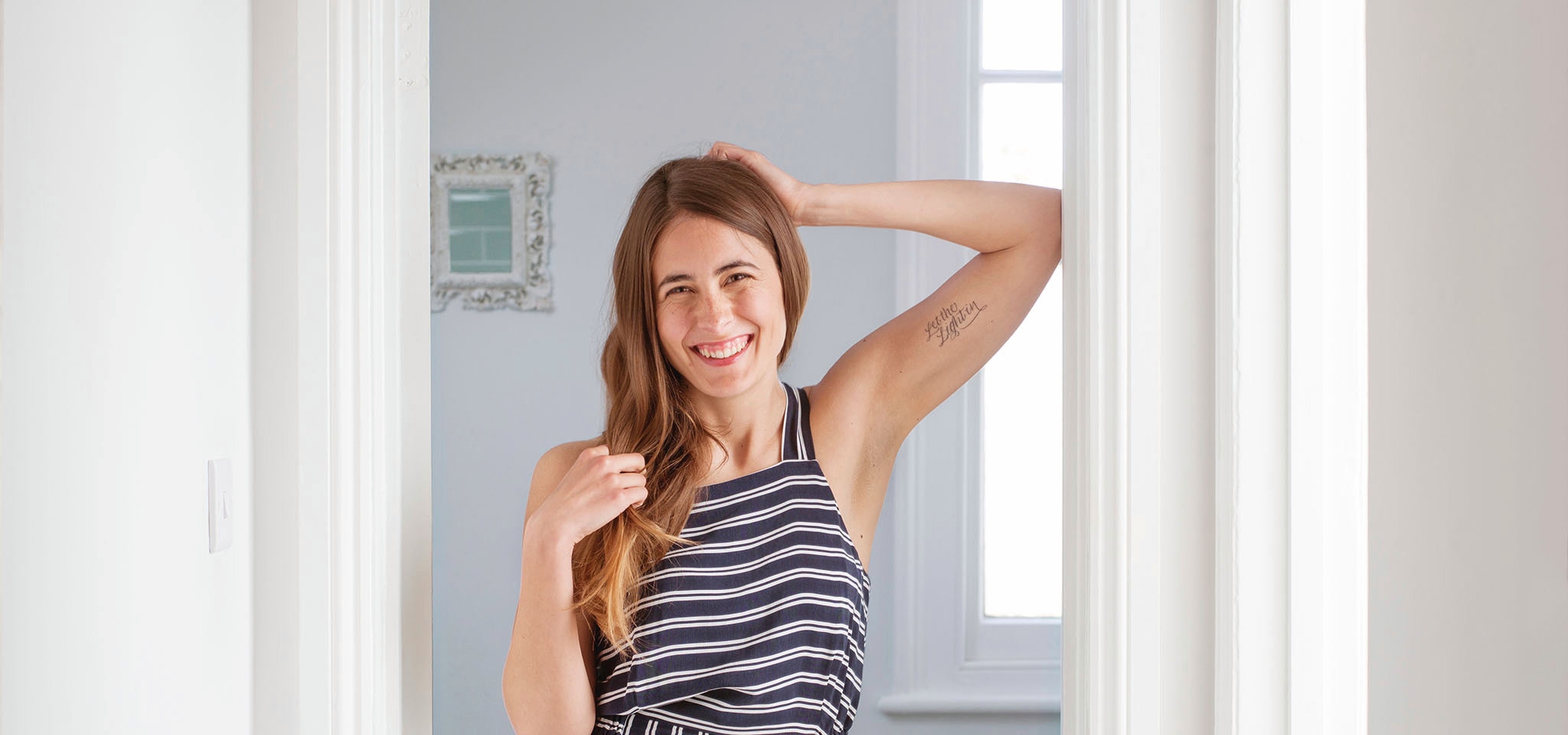 Woman wearing dress with long hair smilingly with one arm up