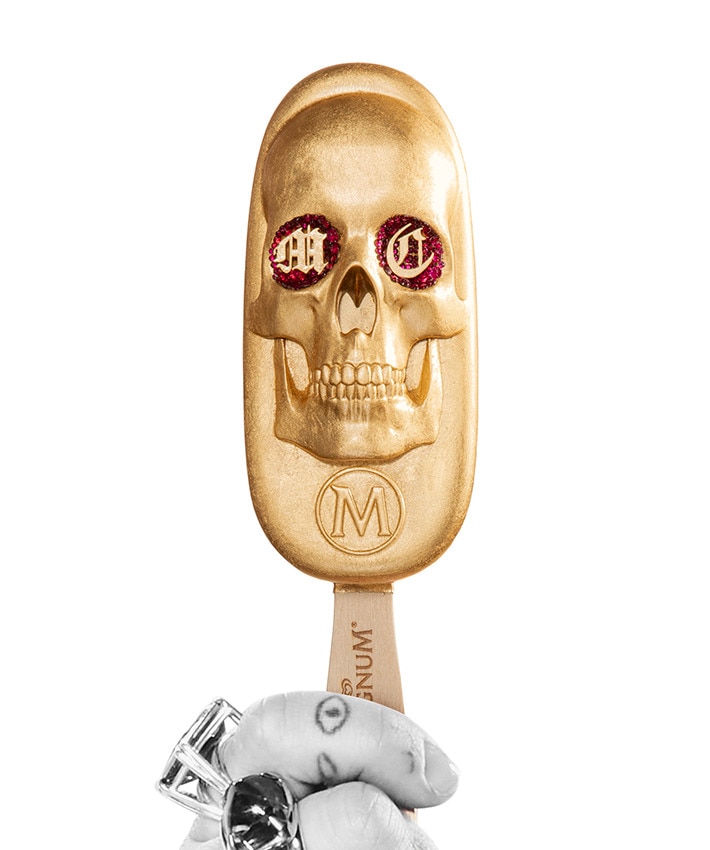Close up hand of Miley Cyrus holding her gold replica skull shaped magnum ice cream